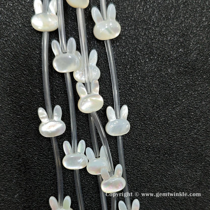 Close up view of carved white shell rabbit charms showing ear profile