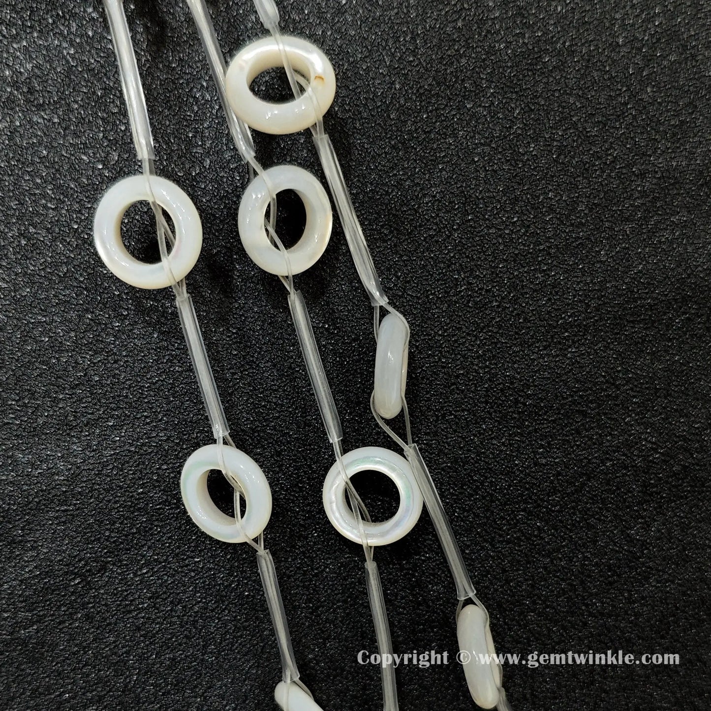 Close up view of double sided white shell round ring charms with iridescent luster
