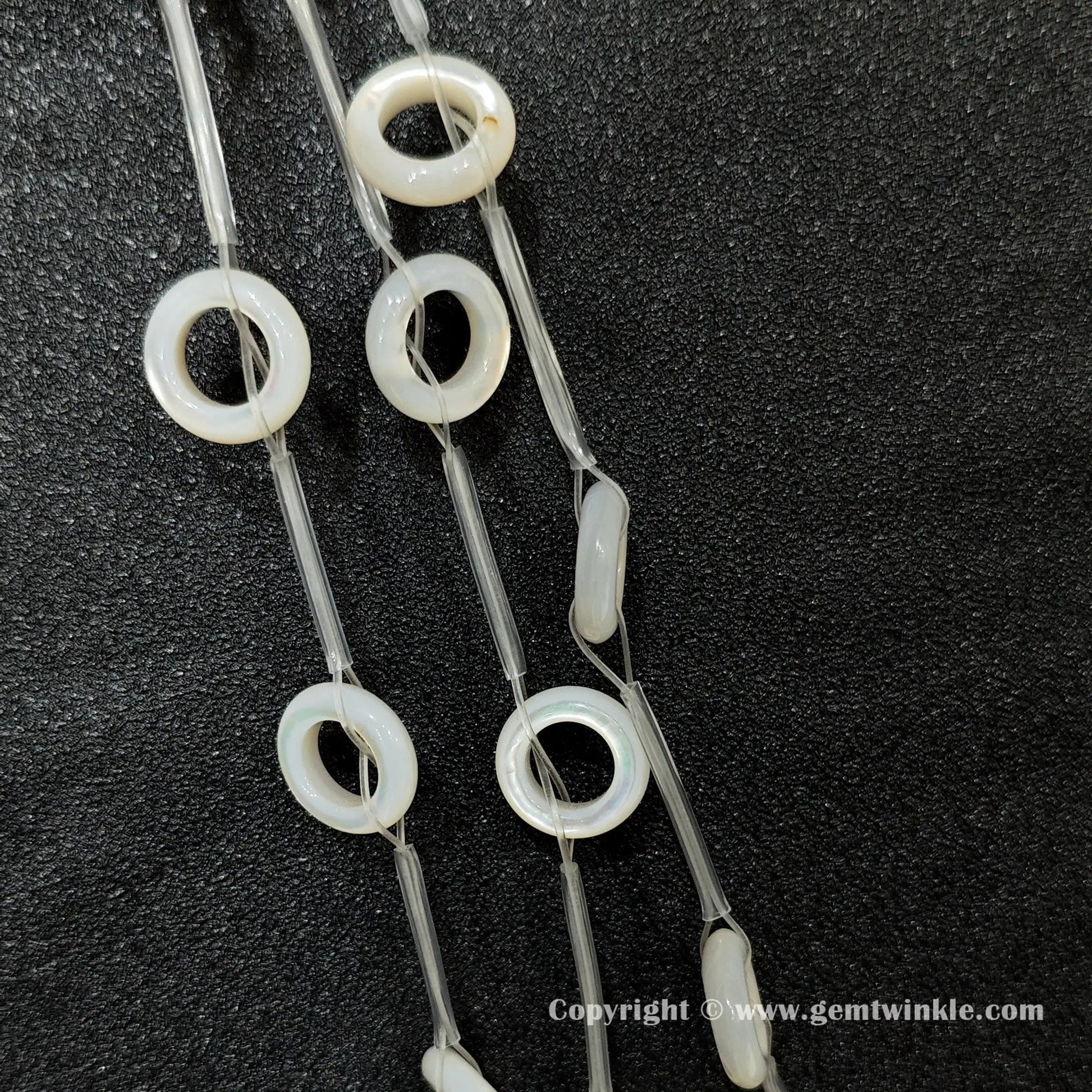 Close up view of double sided white shell round ring charms with iridescent luster