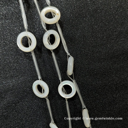Close up view of double sided white shell round ring charms with iridescent luster