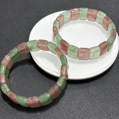  Close-up view of two Natural Pink & Green Strawberry Quartz Bangle Bracelets on a white plate, highlighting the texture and color details of the square beads.