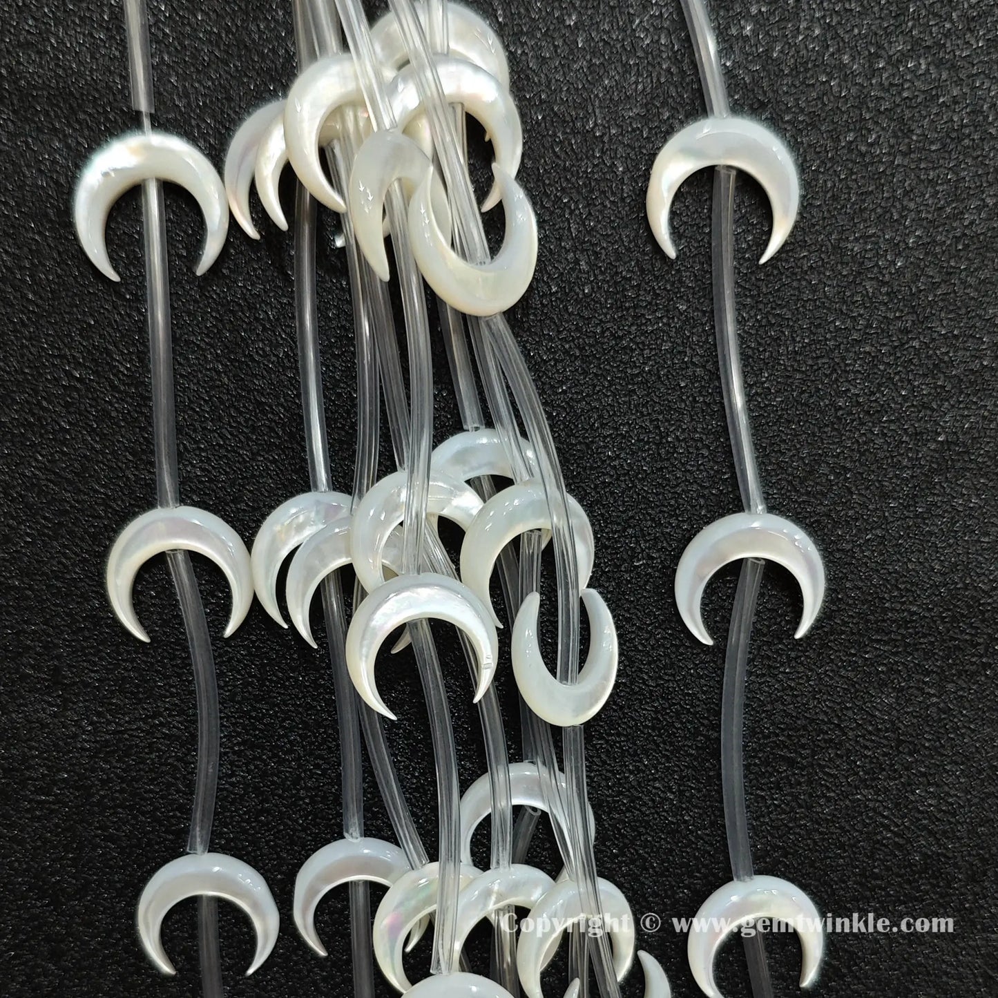 Close up view of white shell machine carved crescent moon charms