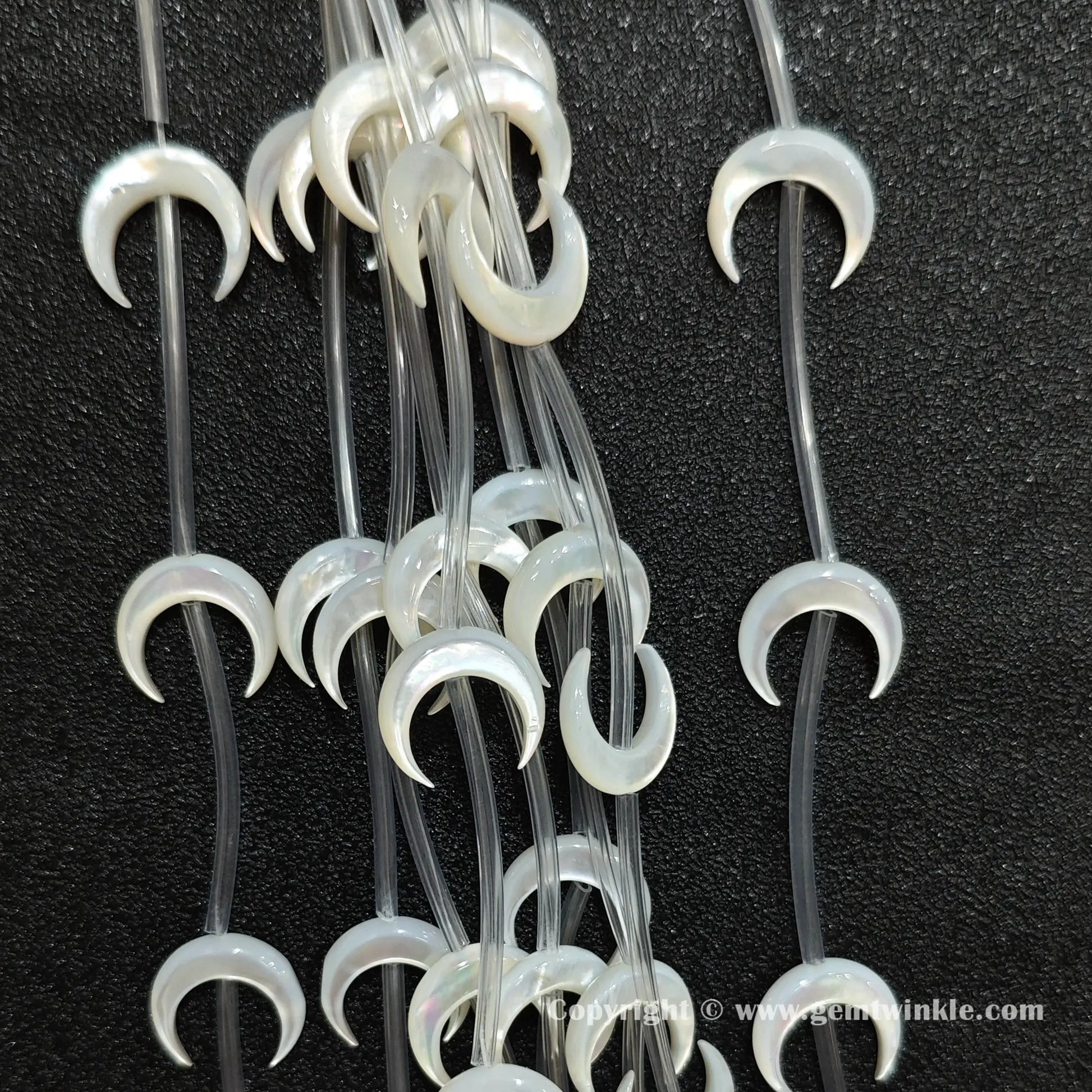 Close up view of white shell machine carved crescent moon charms