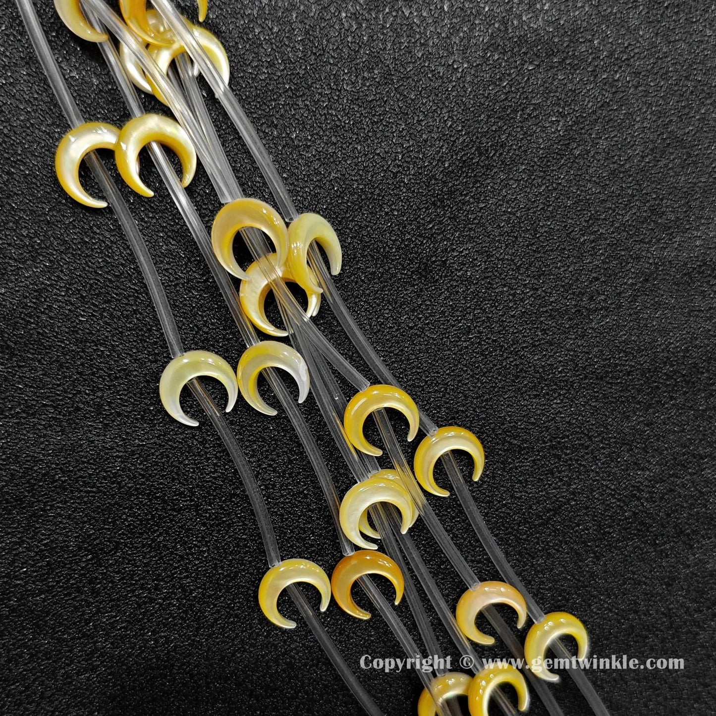 Close up view of golden yellow shell machine carved crescent moon charms