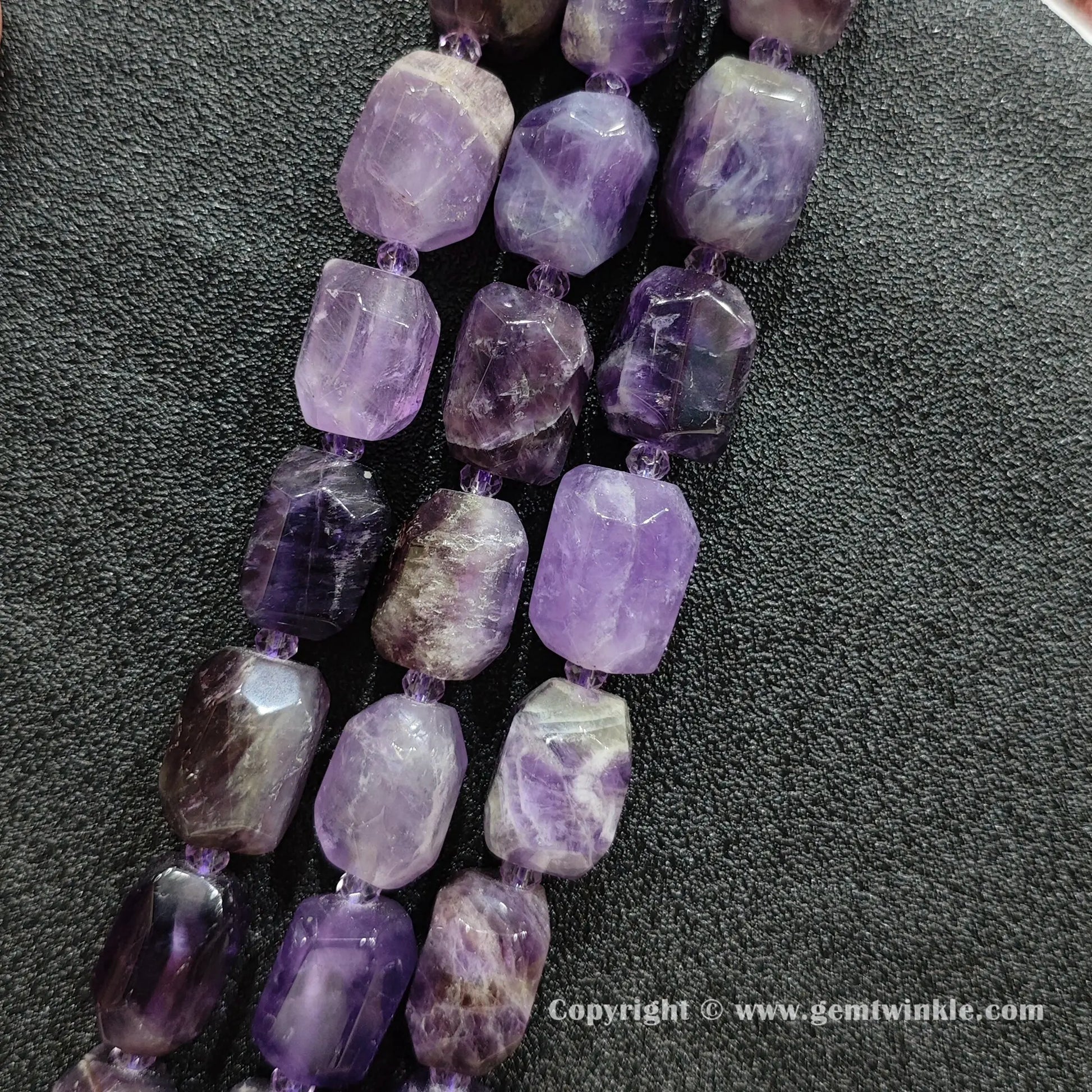close up of faceted purple amethyst cylinder beads with white quartz inclusions
