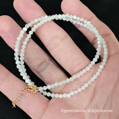 White Moonstone rates 6 to 6.5 on the Mohs scale and possesses natural cleavage lines. Clean gently using warm water with mild soap and a soft cloth; avoid ultrasonic cleaners, thermal shock, and harsh chemicals. Store separately from harder gemstones to prevent surface abrasion, and keep the gold-tone extender chain dry to protect its polished finish.