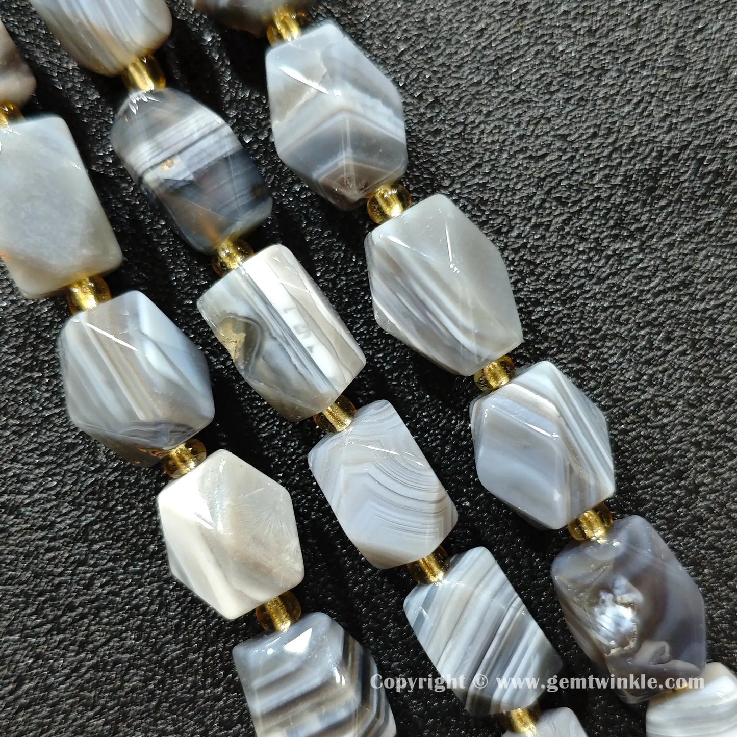close up of persian agate cylinder beads showing parallel grey and white banding
