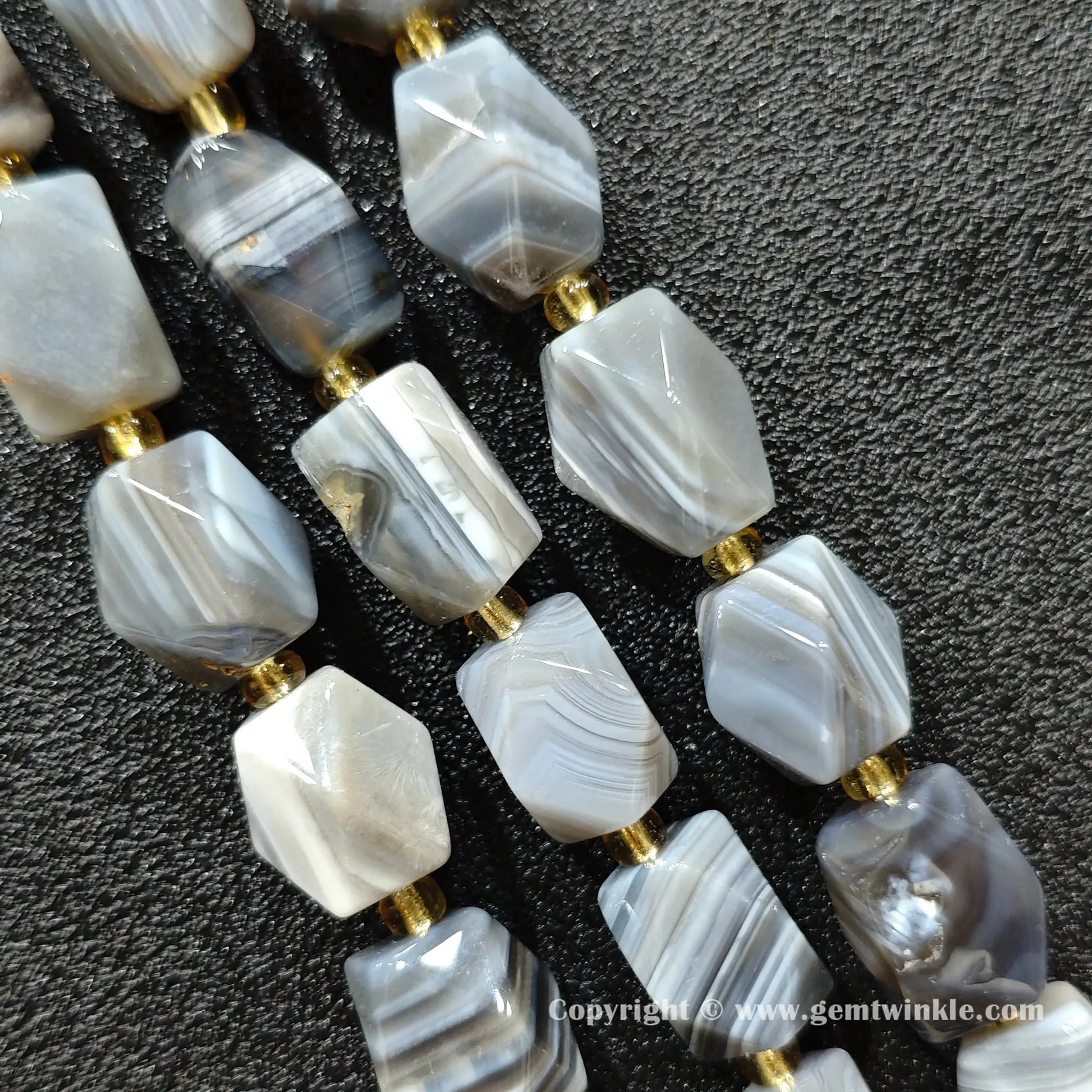 close up of persian agate cylinder beads showing parallel grey and white banding