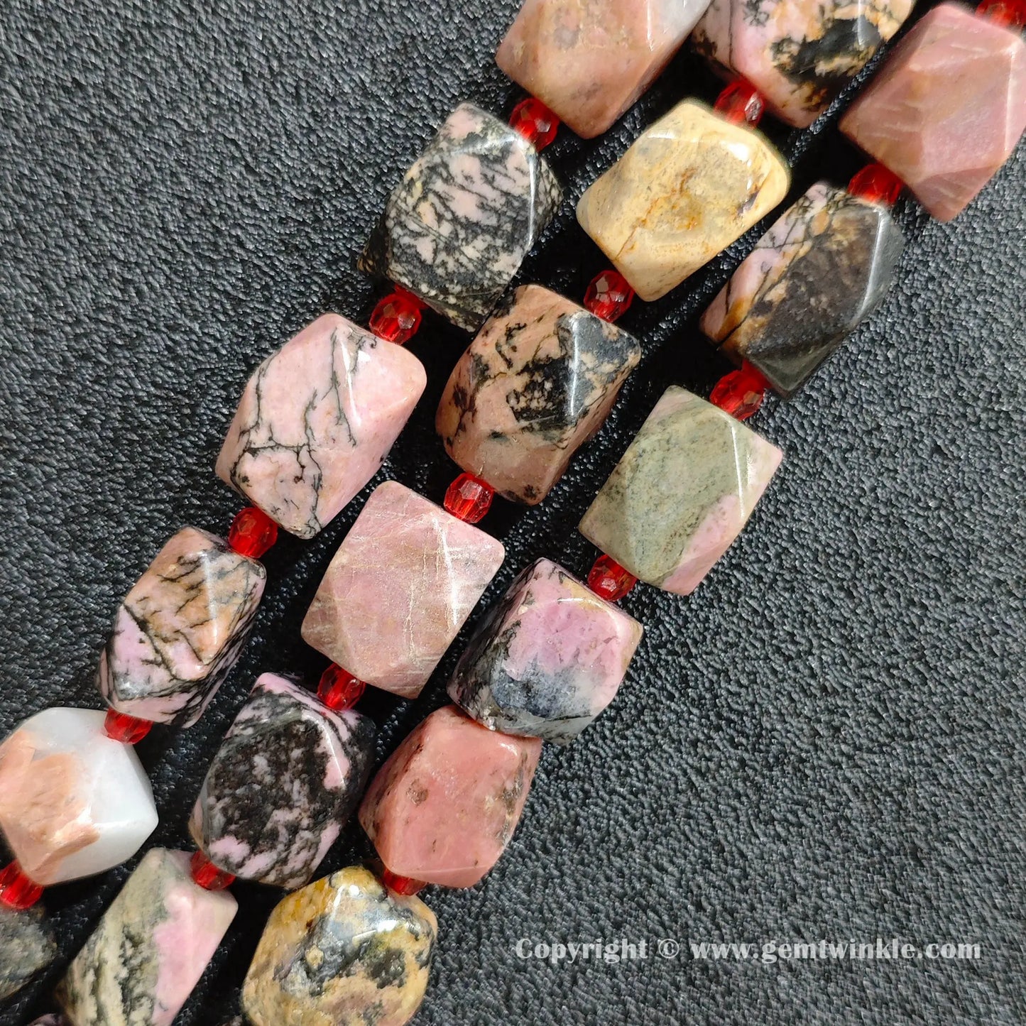 close up of pink rhodonite cylinder beads showing black manganese matrix