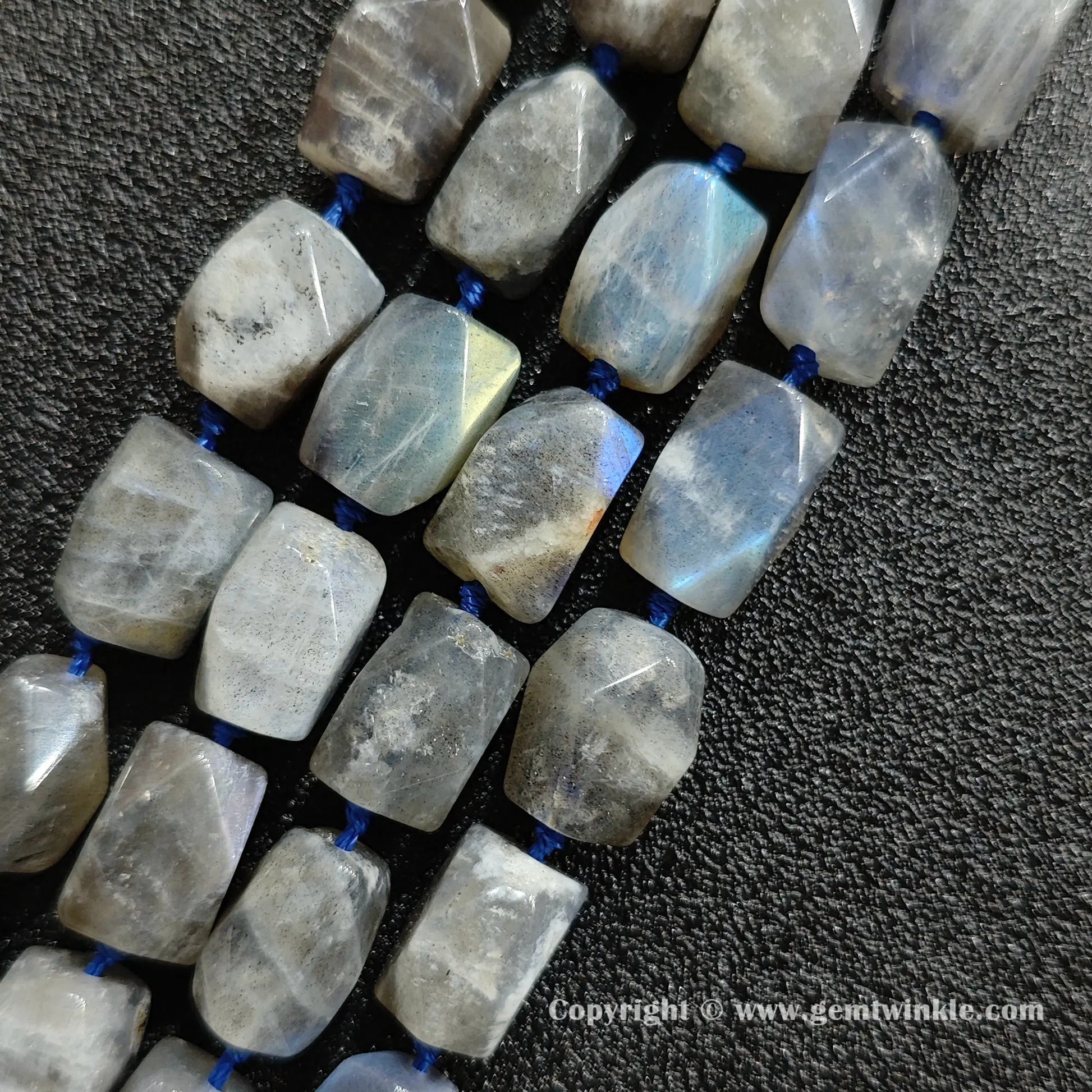 close up of raw cut grey moonstone cylinder beads with blue schiller flash