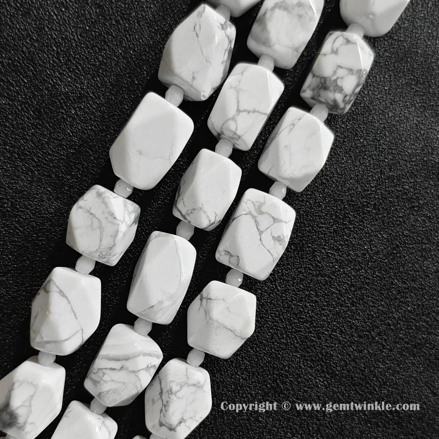 close up view of spiderweb matrix white magnesite faceted cylinder beads