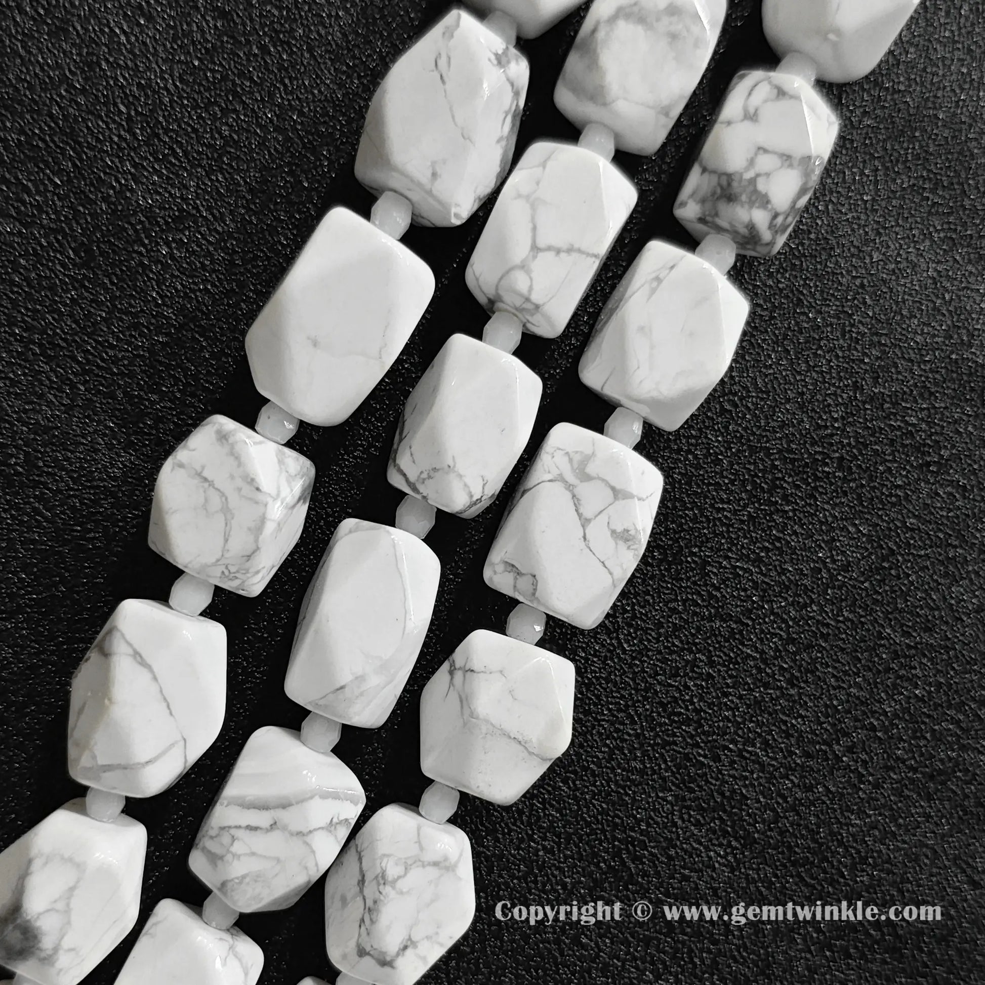 close up view of spiderweb matrix white magnesite faceted cylinder beads