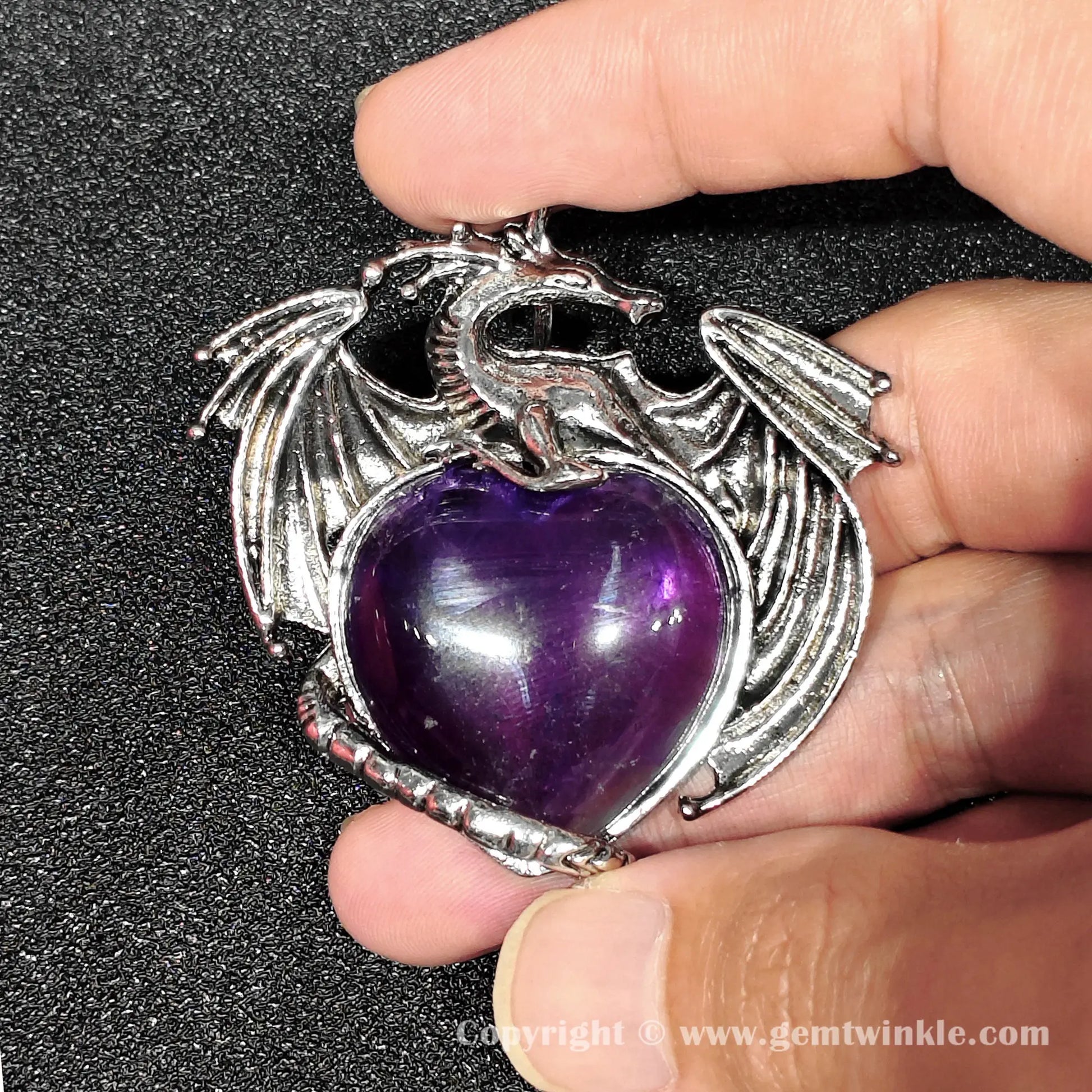 Hand holding 5cm dragon heart amethyst pendant with visible natural internal cloud inclusions