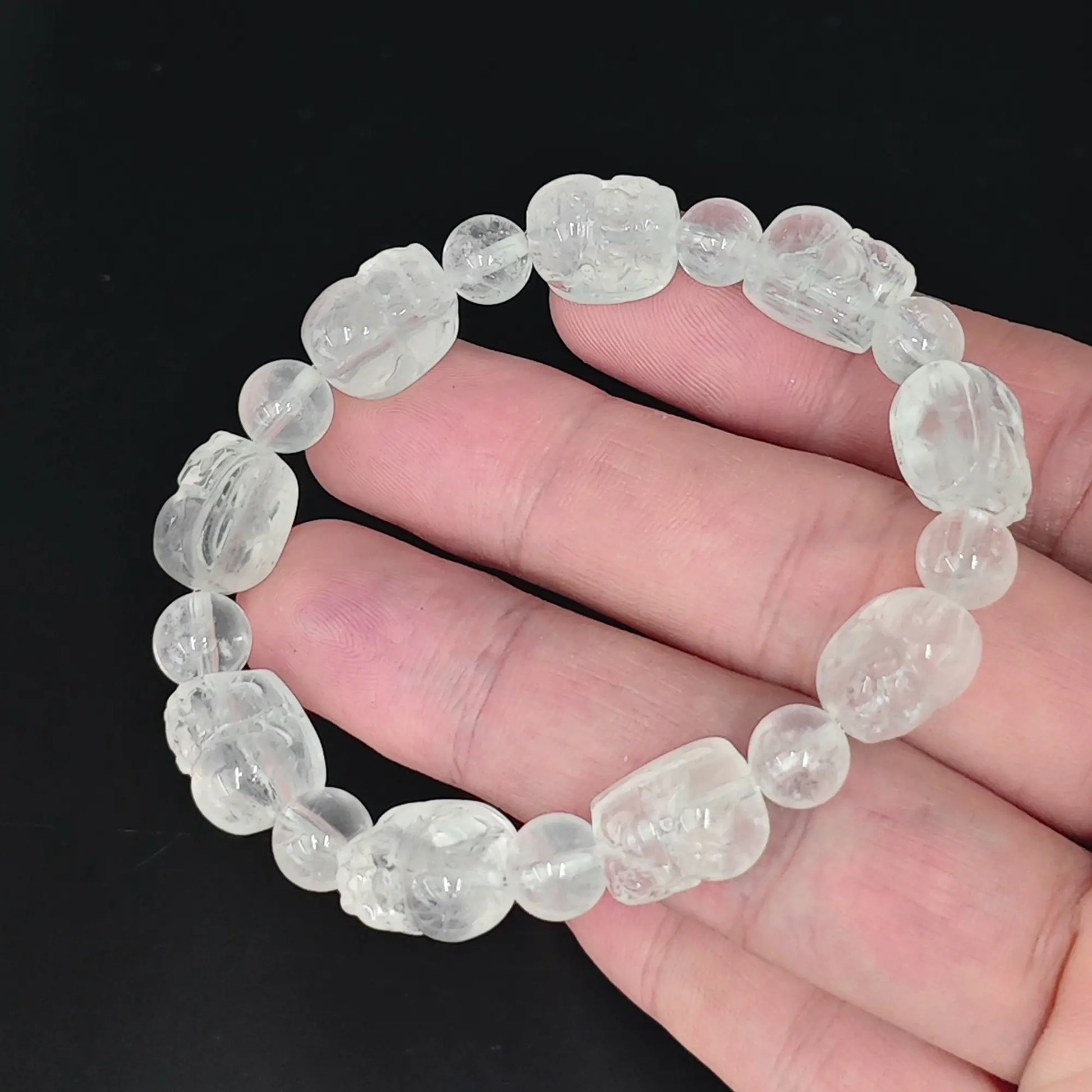 hand holding cloudy quartz pixiu carved beads stretch bracelet with ice fractures