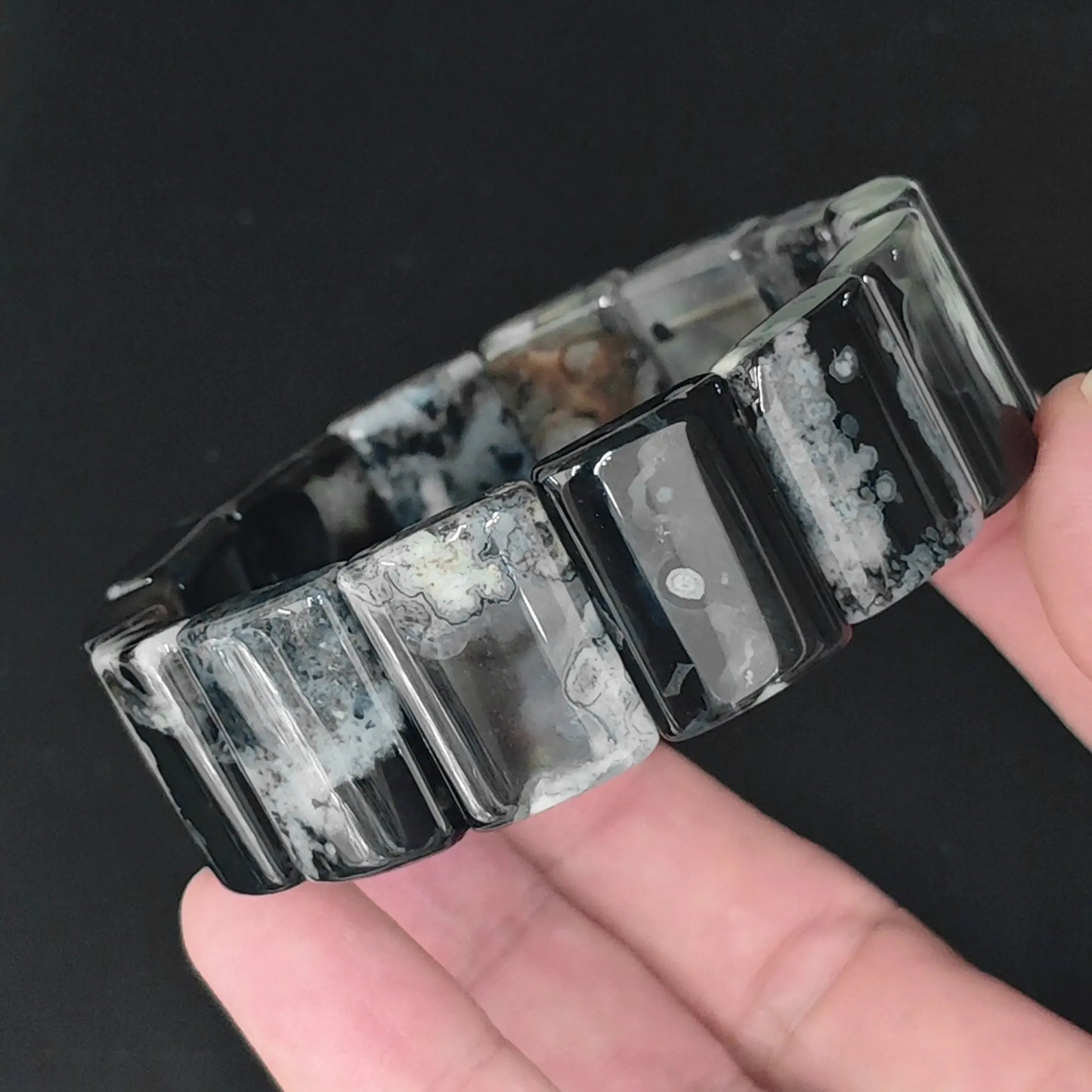 Color dyed black sakura agate 20x15mm rectangle plate bead bracelet held in hand showing white floral inclusions