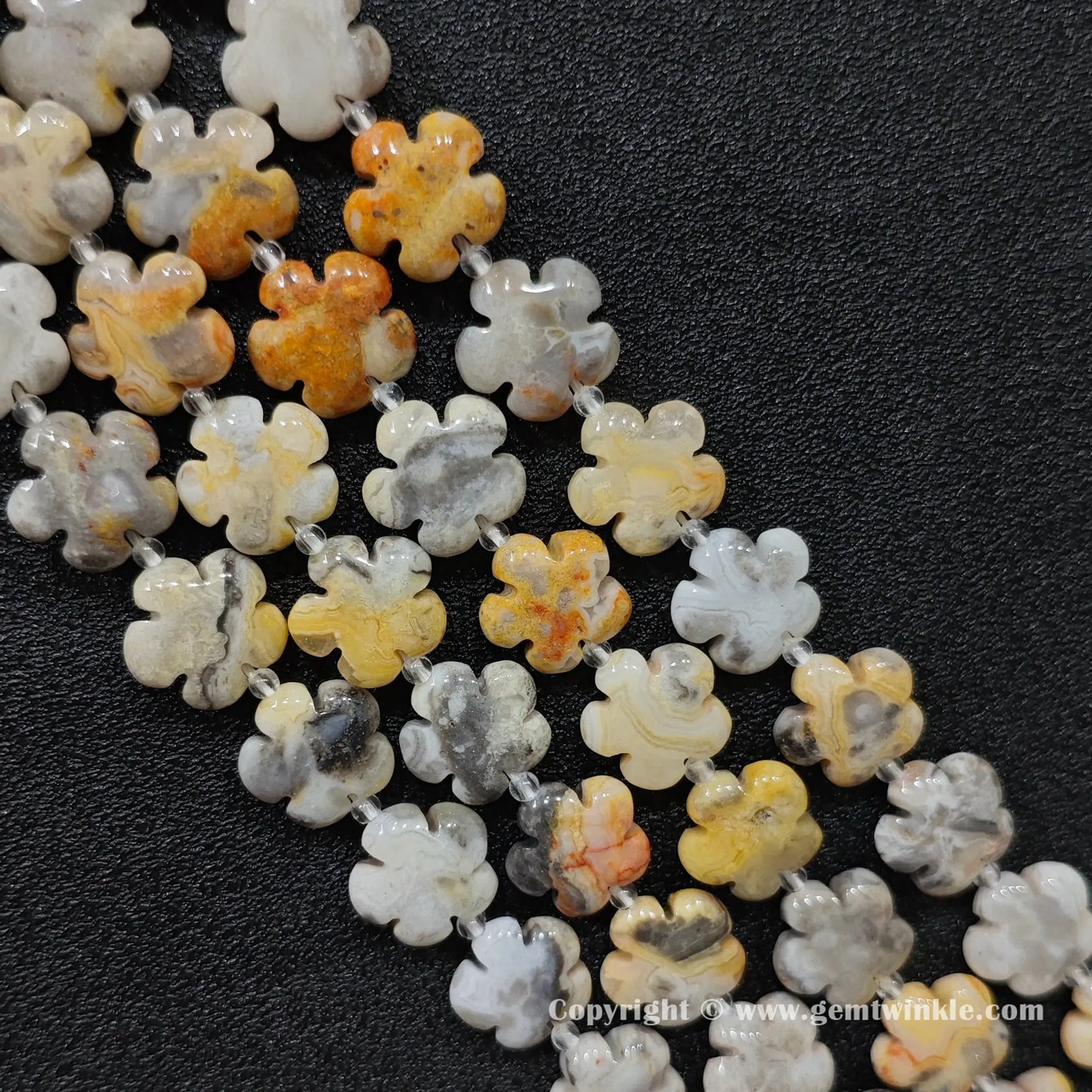 Natural crazy lace agate plum blossom carved bead strand held over hand showing size scale
