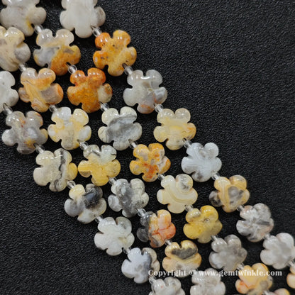 Natural crazy lace agate plum blossom carved bead strand held over hand showing size scale
