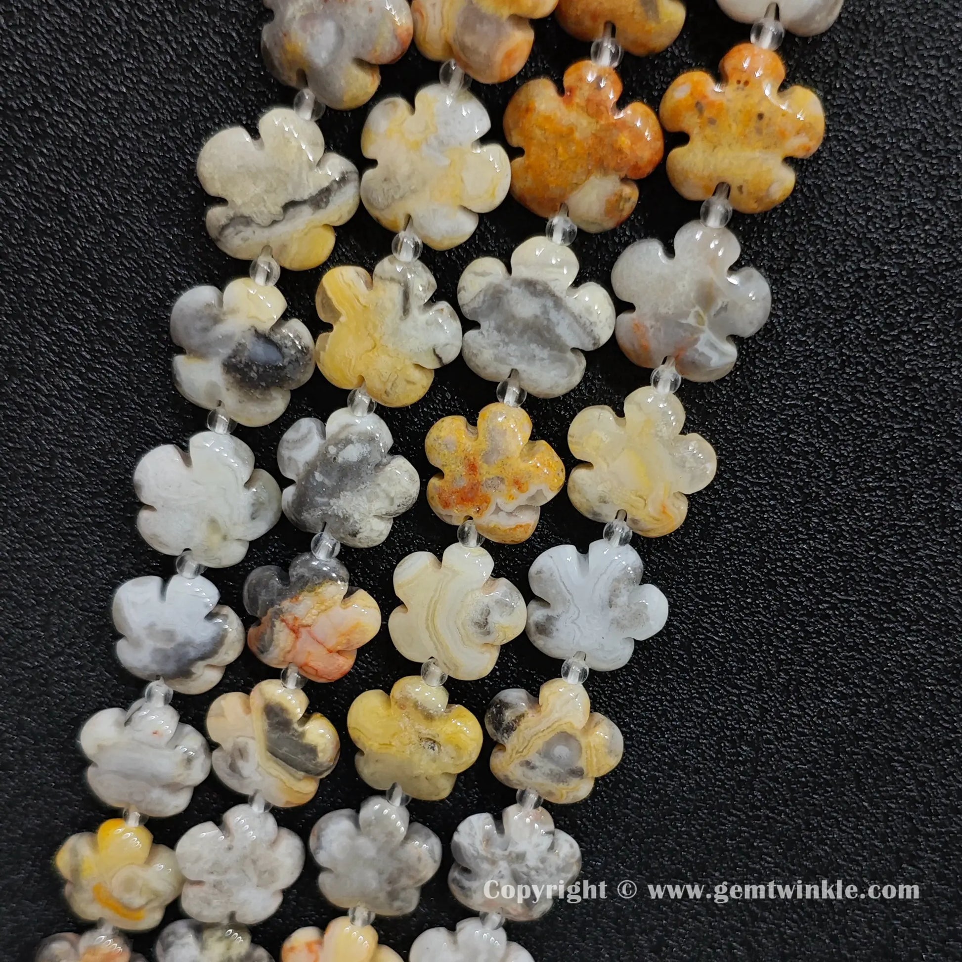 Angled view of natural crazy lace agate floral carved gemstone strands laid together