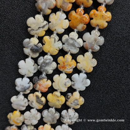 Angled view of natural crazy lace agate floral carved gemstone strands laid together