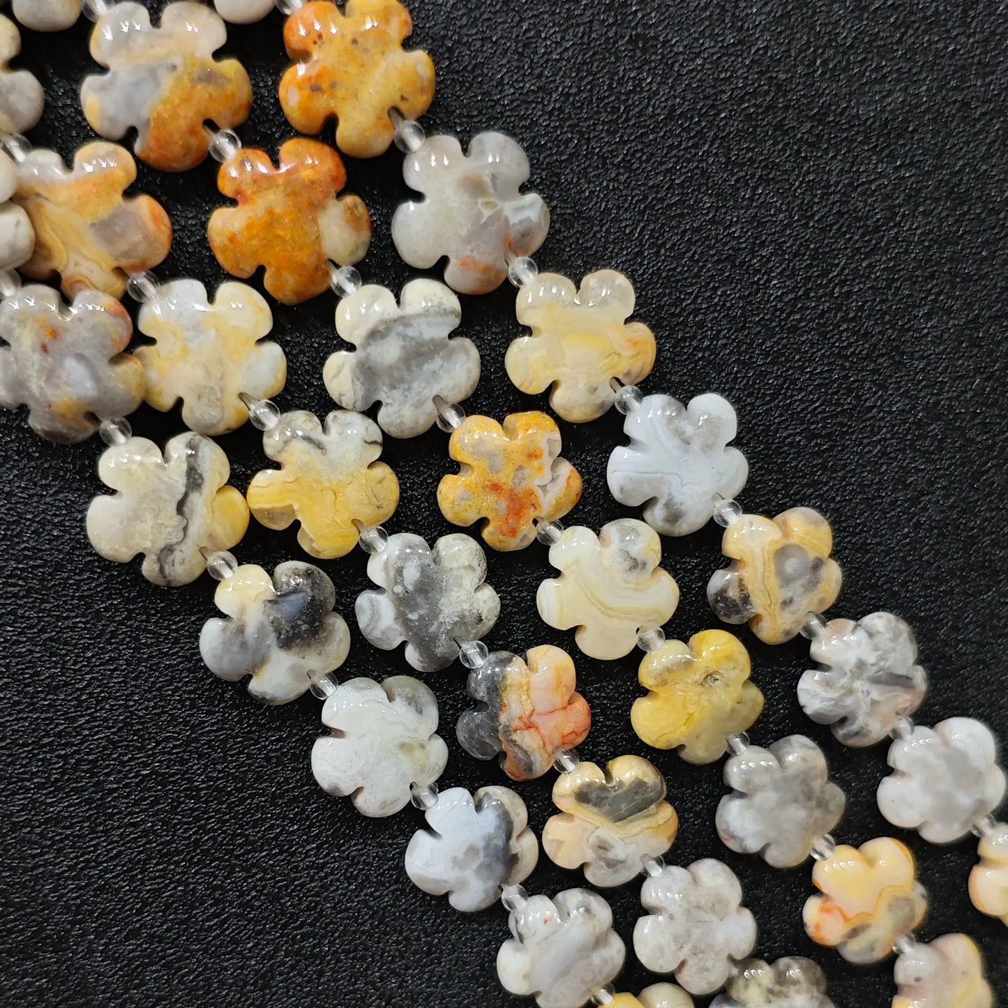 Macro closeup of crazy lace agate plum blossom carved beads 15mm showing yellow grey banded swirls