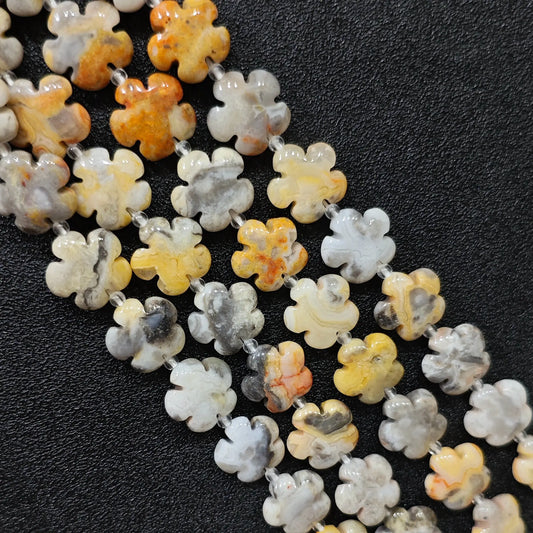 Macro closeup of crazy lace agate plum blossom carved beads 15mm showing yellow grey banded swirls