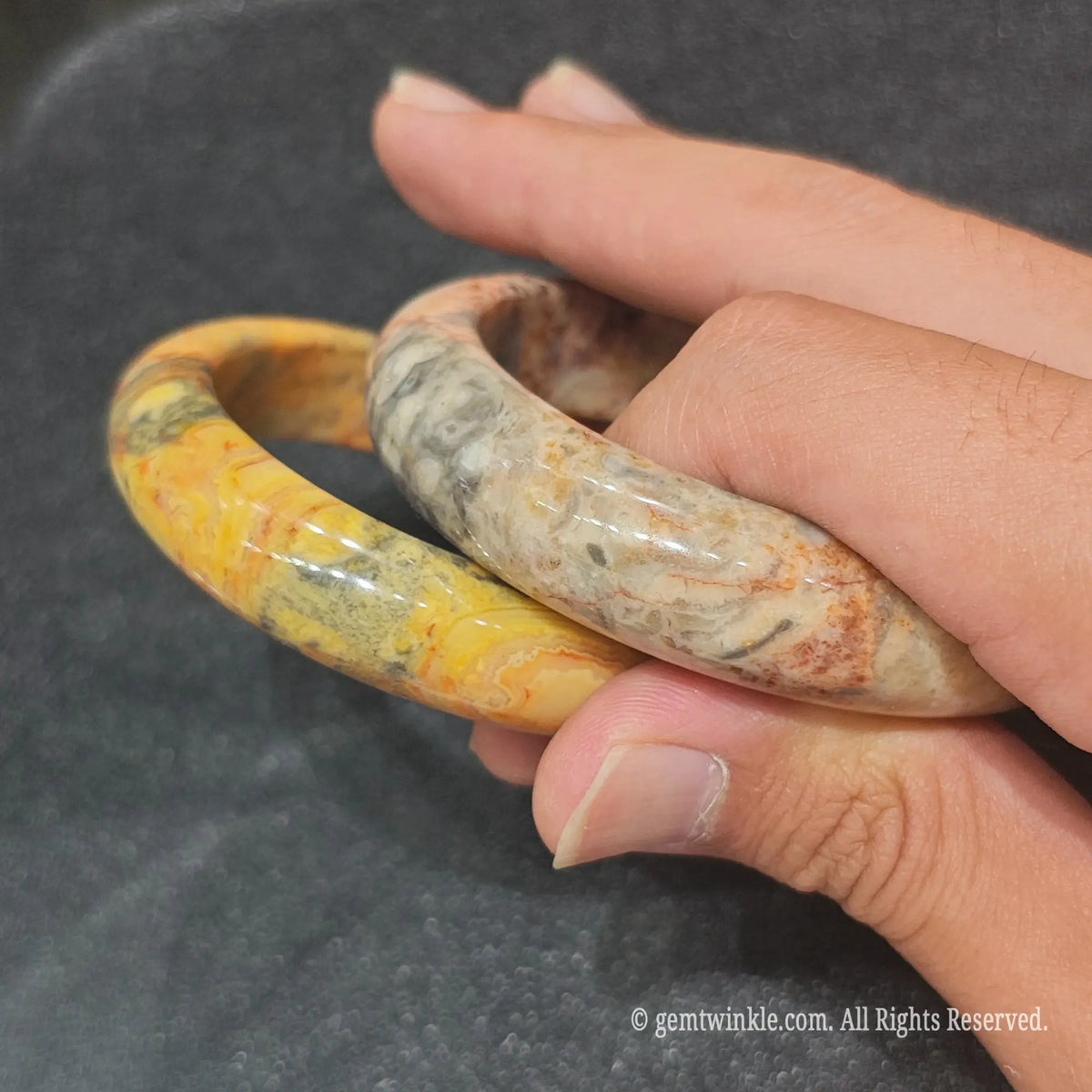 Pair of authentic carved Crazy Lace Agate bangles showing intricate multi-colored swirl patterns