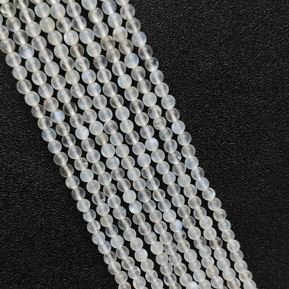 Macro closeup of creamy blue flash moonstone smooth round beads showing vivid optical blue sheen