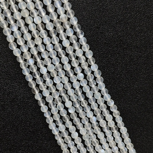 Macro closeup of creamy blue flash moonstone smooth round beads showing vivid optical blue sheen