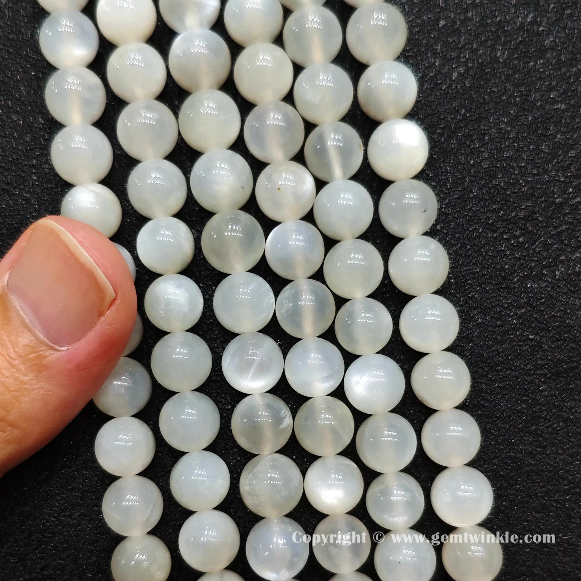 Perspective view of creamy white moonstone round beads showing polished finish across multiple sizes