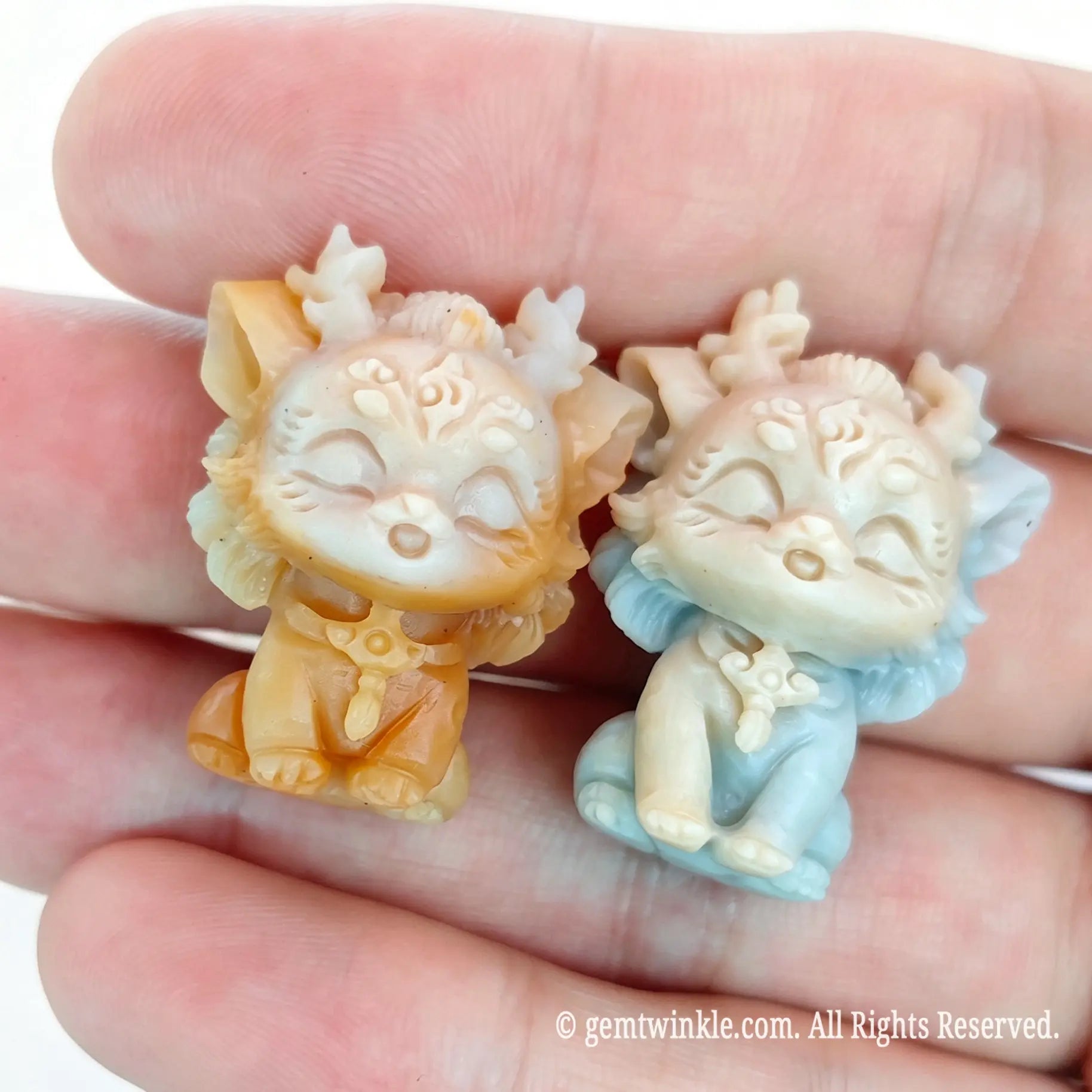 Miniature natural Alashan agate carved dragon statues resting on open palm highlighting 25mm pocket size and fine carving details