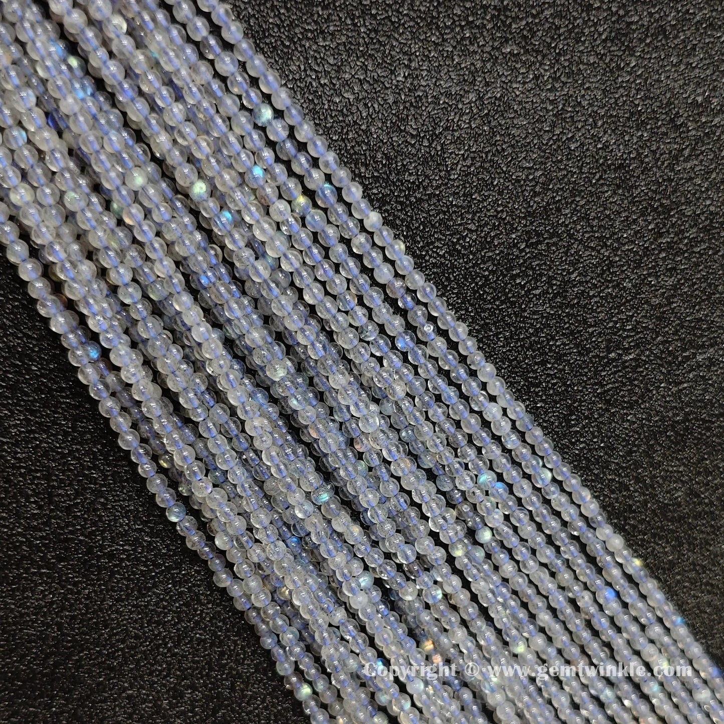 Parallel row arrangement of dainty 2-4mm natural grey blue moonstone round strands with glossy polish