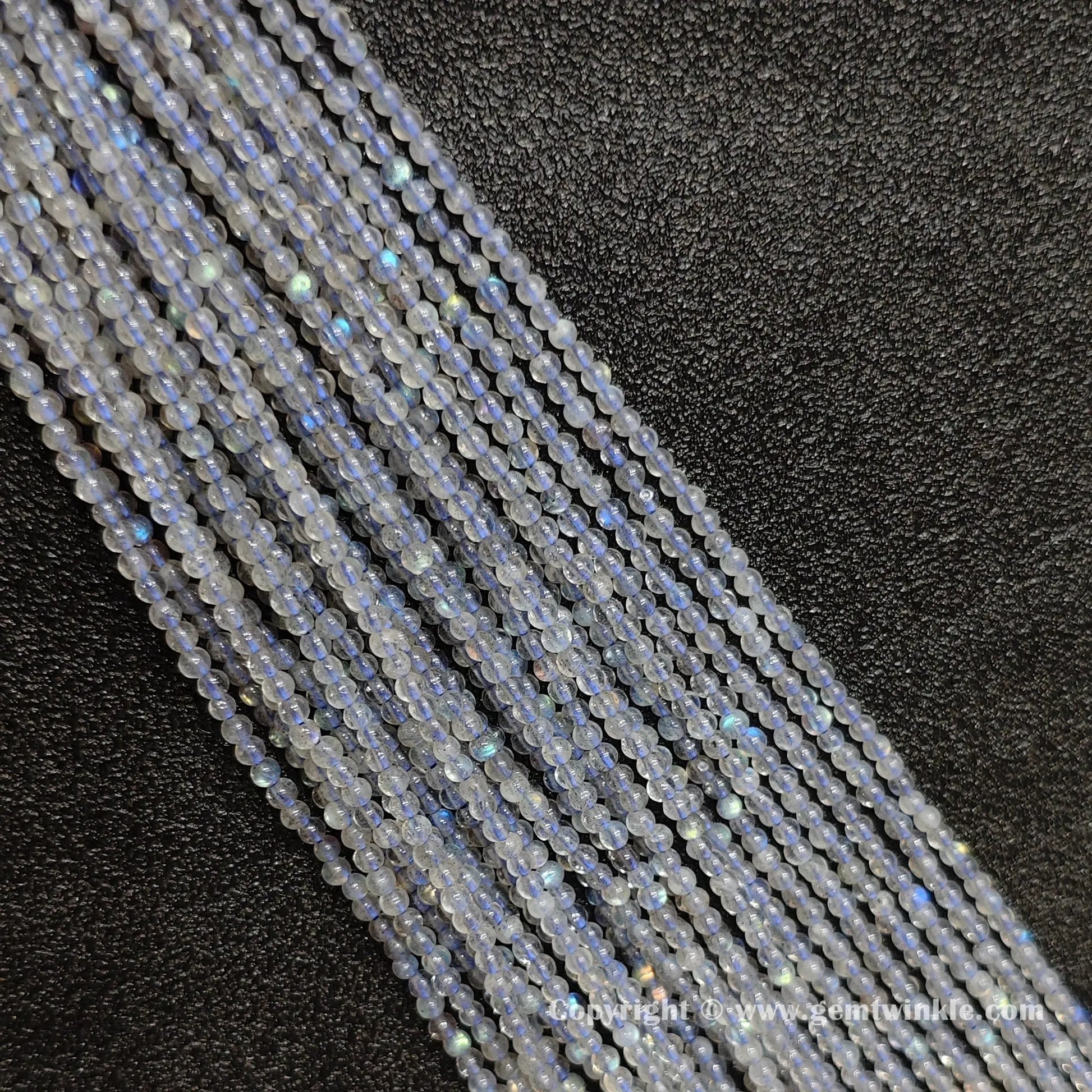 Parallel row arrangement of dainty 2-4mm natural grey blue moonstone round strands with glossy polish