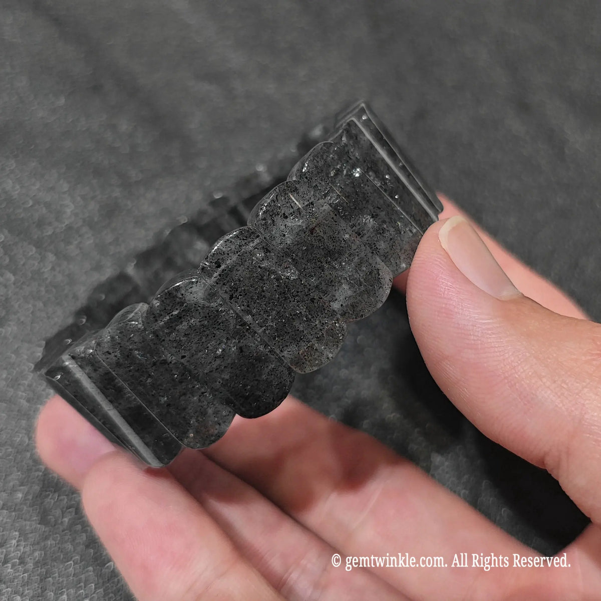 Perspective shot of a dark boho black strawberry quartz flat bead wristlet with dense sparkling inclusions