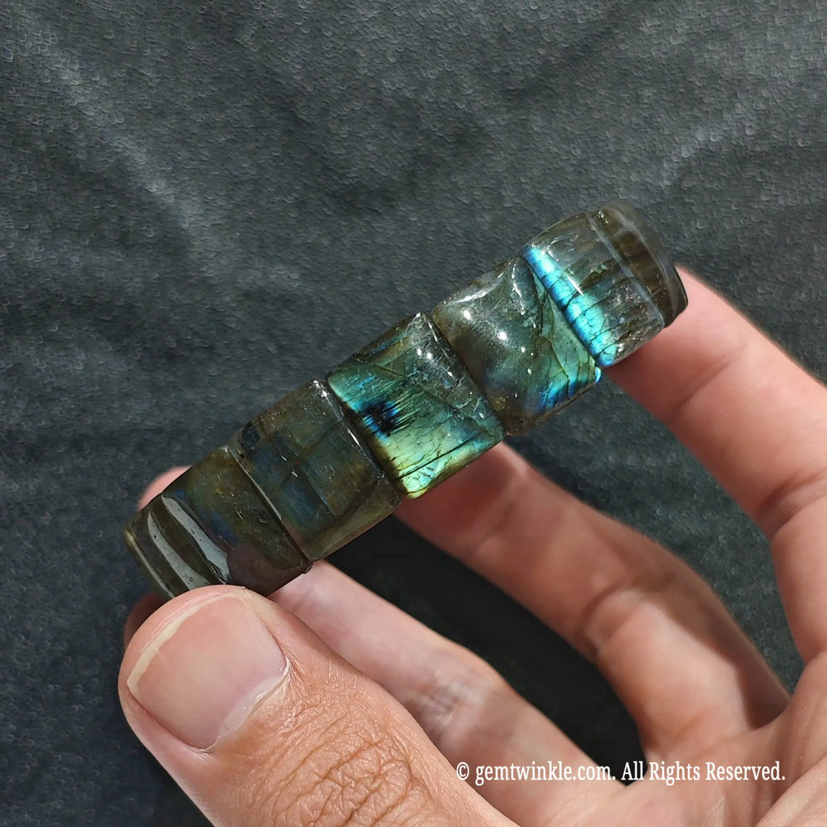 Perspective shot of a dark boho labradorite flat bead strand highlighting natural feldspar inclusions and luster