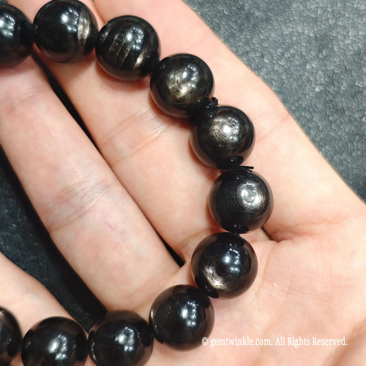 Close up view of dark metallic hypersthene beads showing natural fibrous texture and polished surface