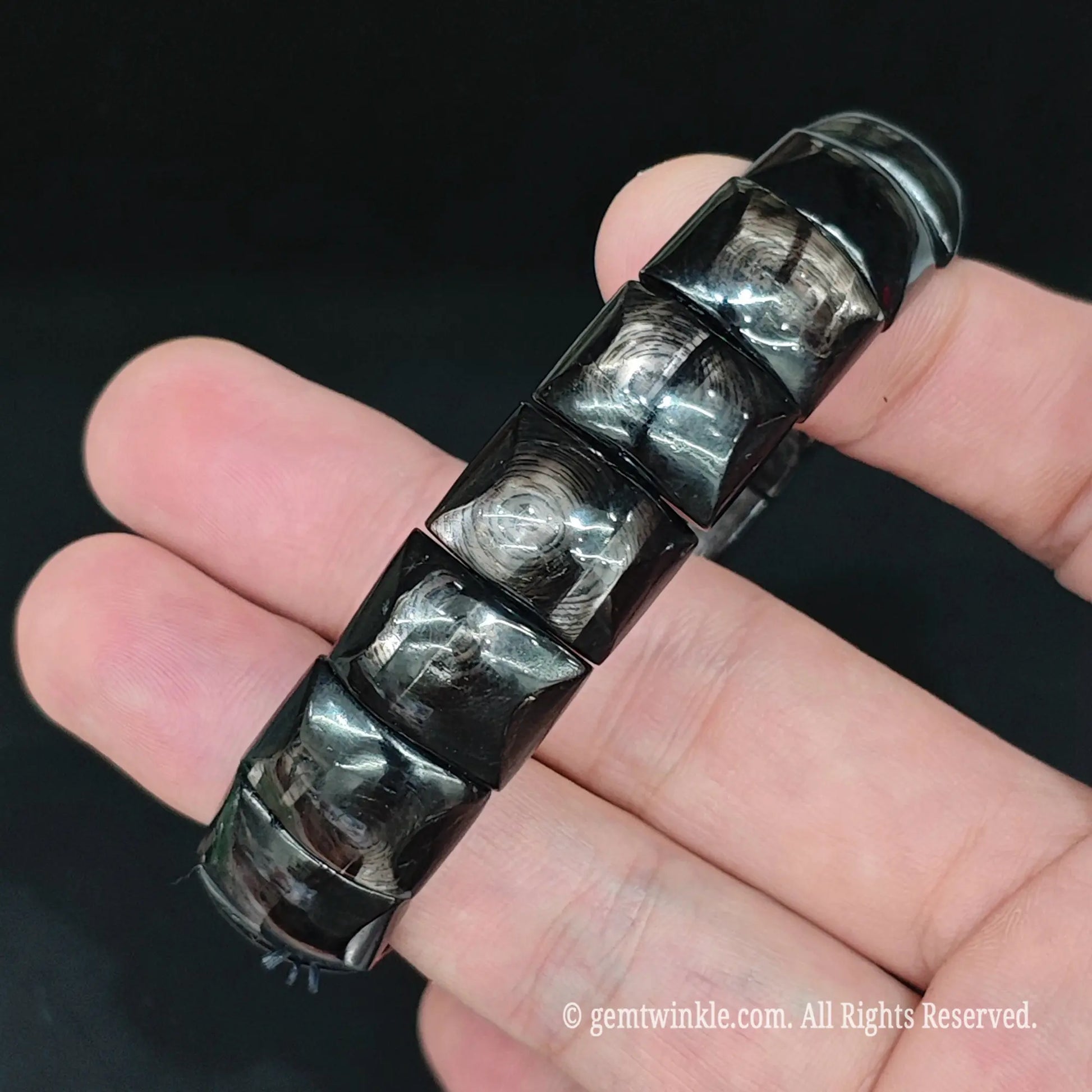 Dark hypersthene curved bar segment stretch bracelet side view highlighting smooth carved joints and uniform tile alignment
