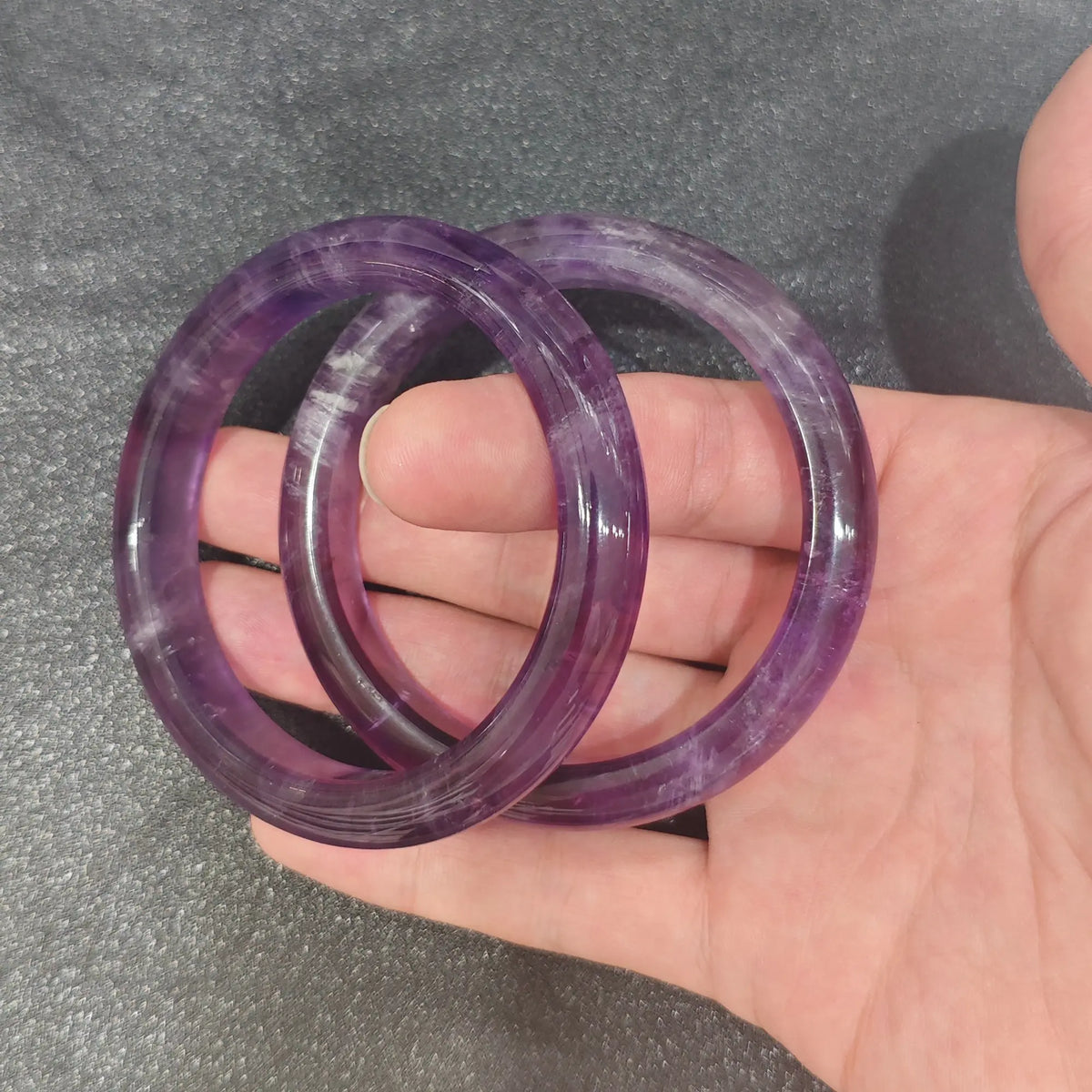 Natural Deep Purple Amethyst solid gemstone bangle bracelet held on hand displaying rich violet translucency