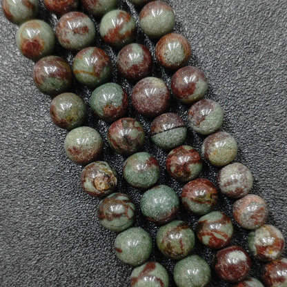 macro view of green phantom quartz crystal beads showcasing rich red hematite accents
