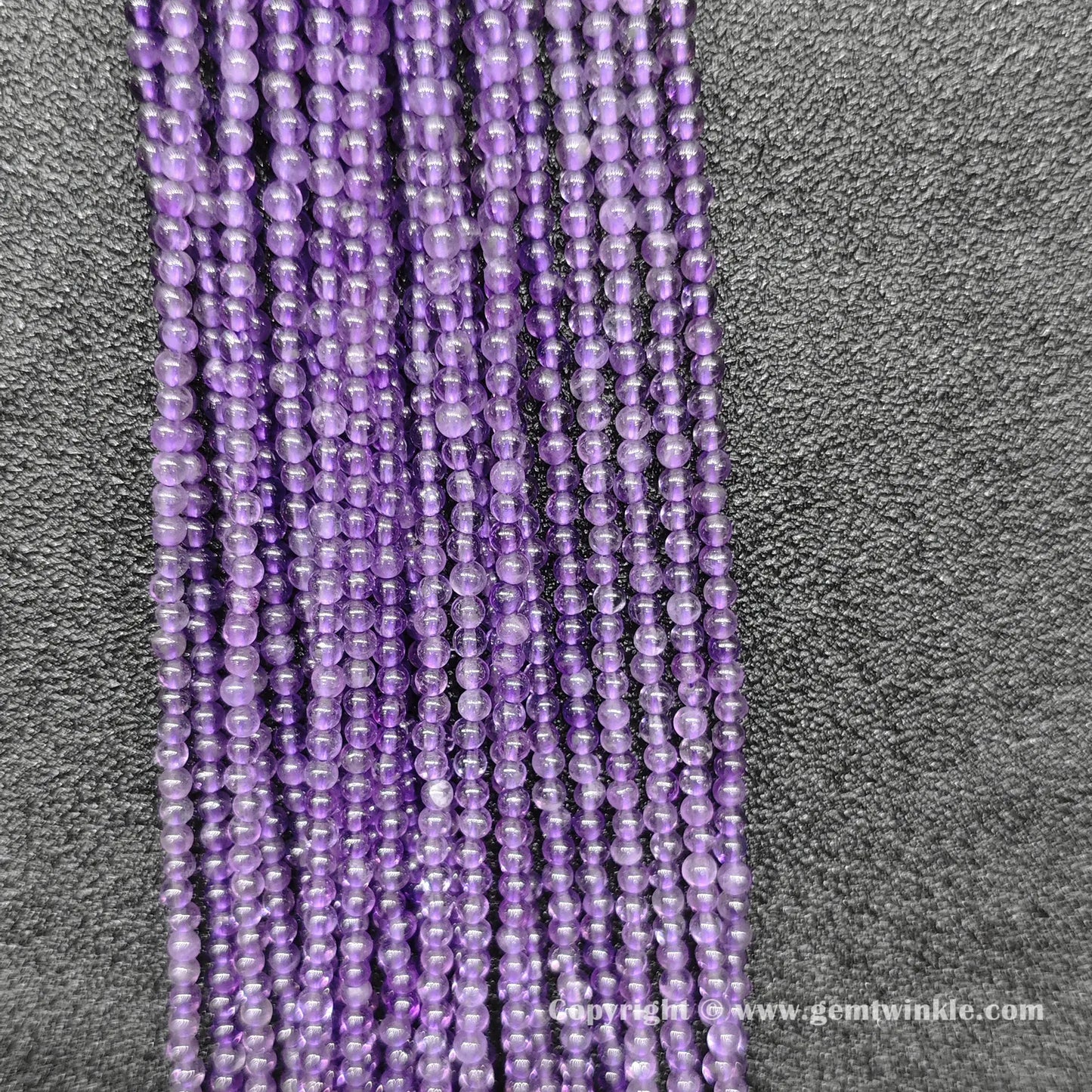 Perspective view of delicate 2mm amethyst loose beads showing smooth micro polish and violet tone