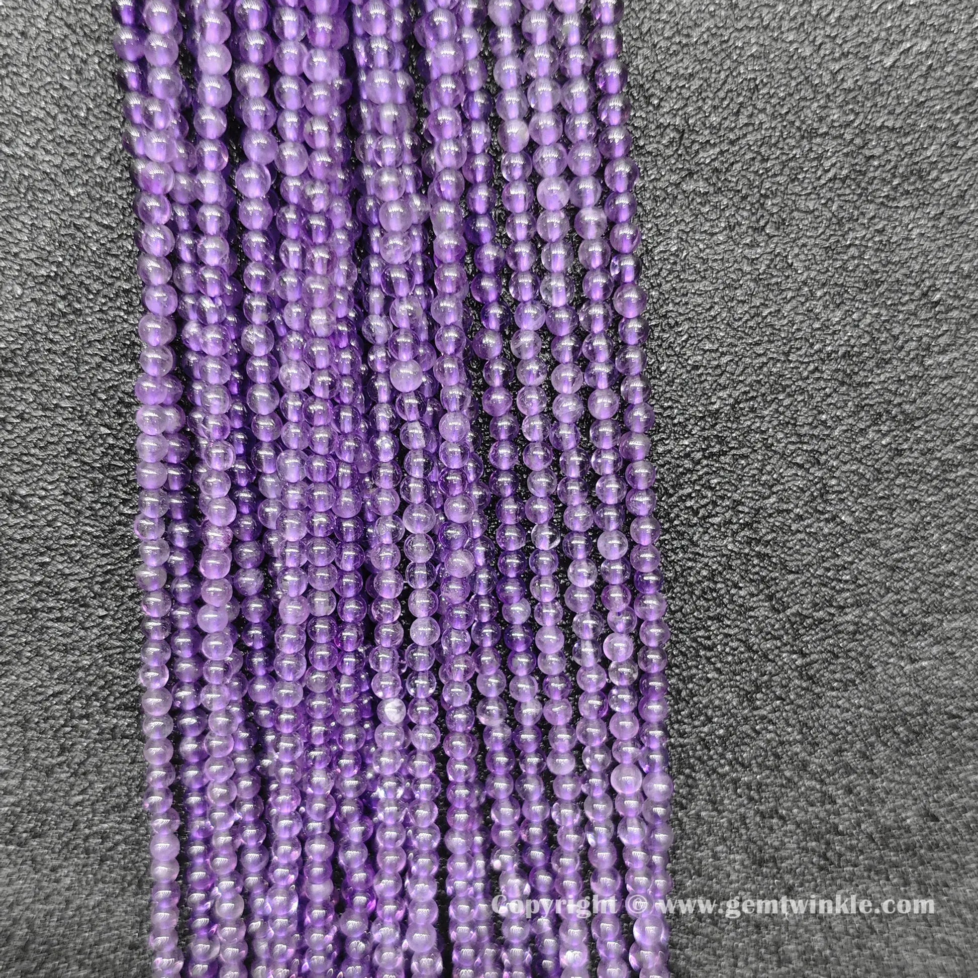 Perspective view of delicate 2mm amethyst loose beads showing smooth micro polish and violet tone