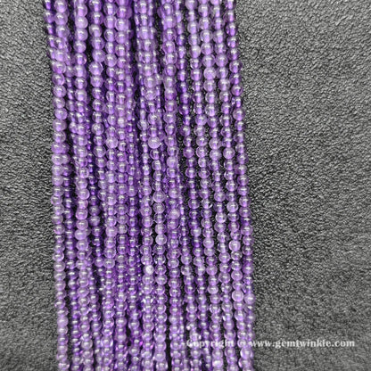 Perspective view of delicate 2mm amethyst loose beads showing smooth micro polish and violet tone