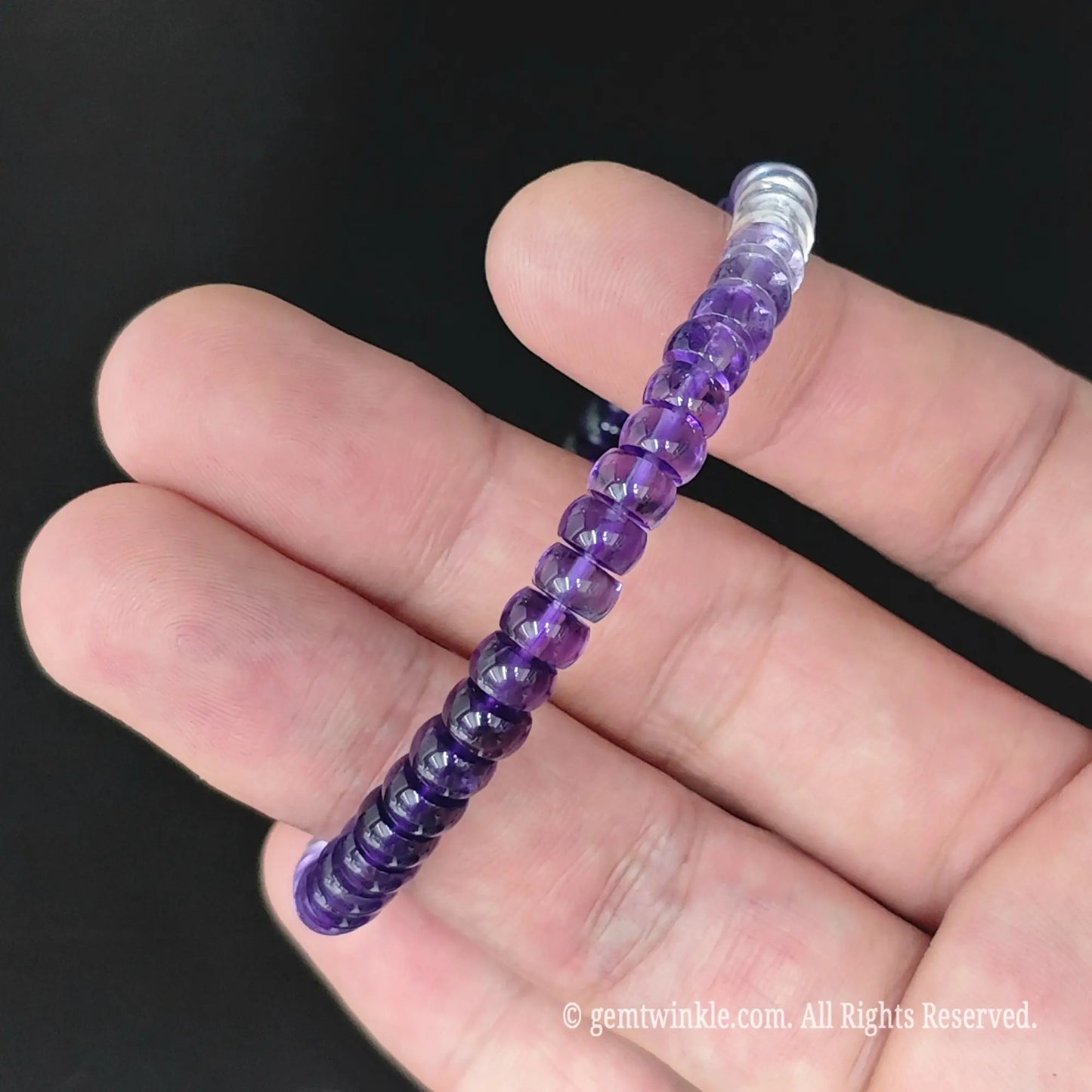 Delicate gradient amethyst disc bead stretch bracelet styled on wrist displaying slim stackable design