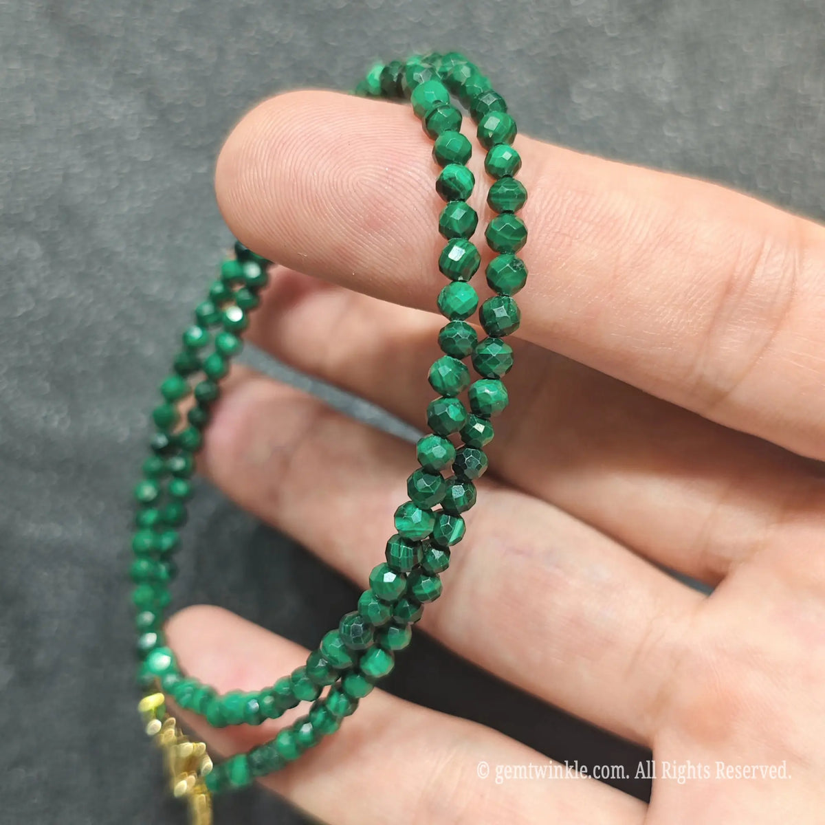 Detailed view of 3mm micro faceted malachite necklace showing multi angle facet polish and green mineral bands