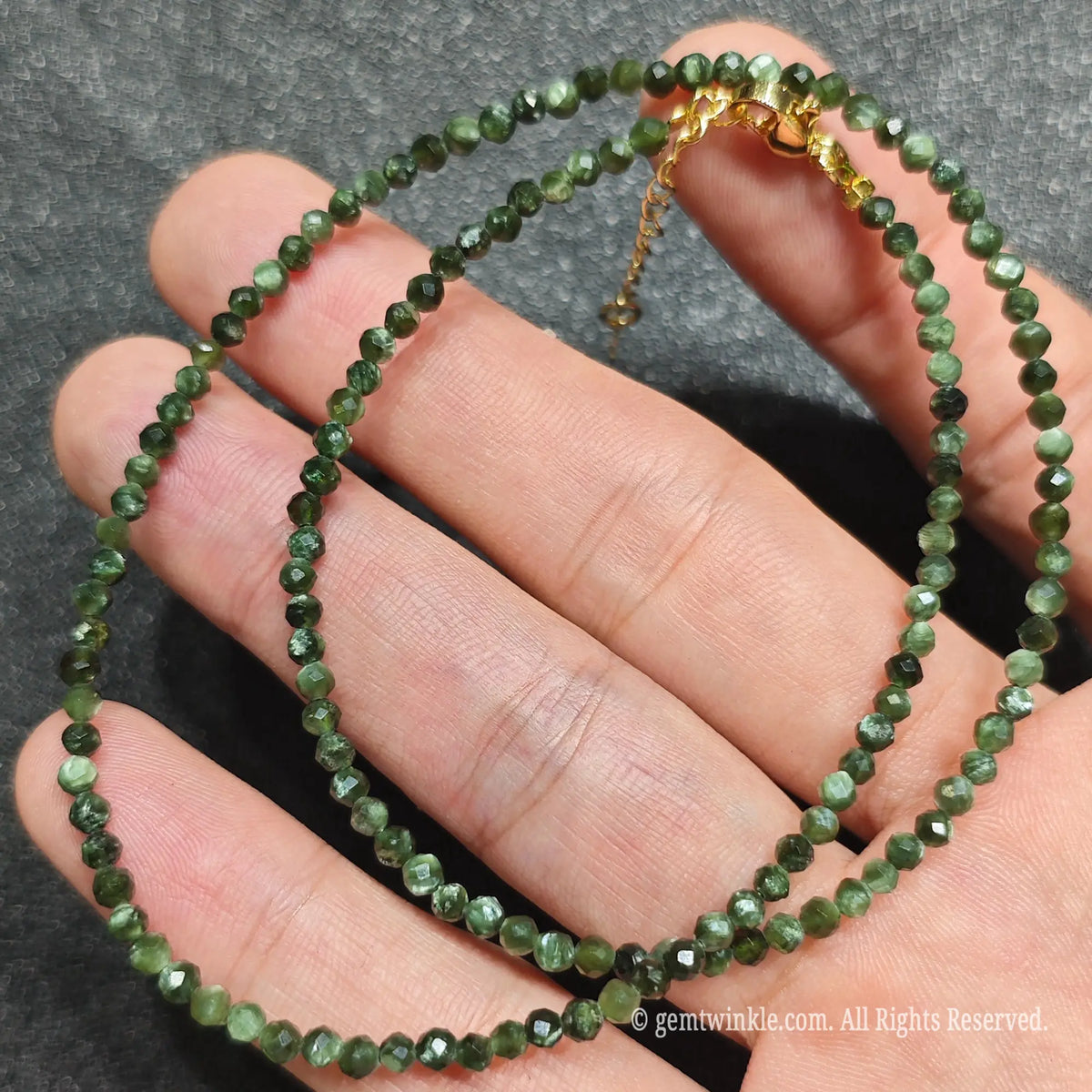 Focus on 3mm seraphinite faceted beads highlighting natural mica feather inclusions and cut facets