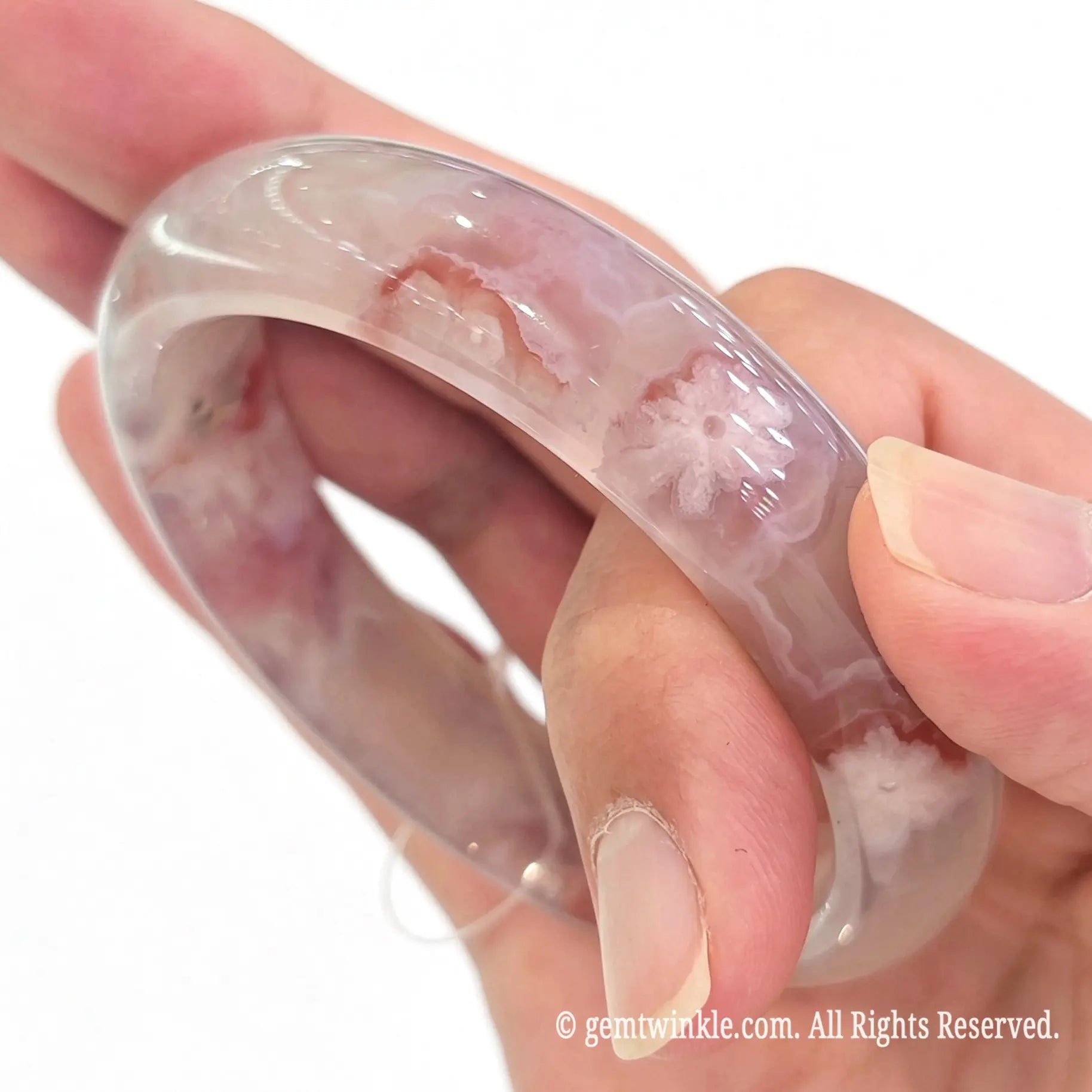 Handheld perspective showing the smooth polished inner band and translucent texture of the blossom agate bangle