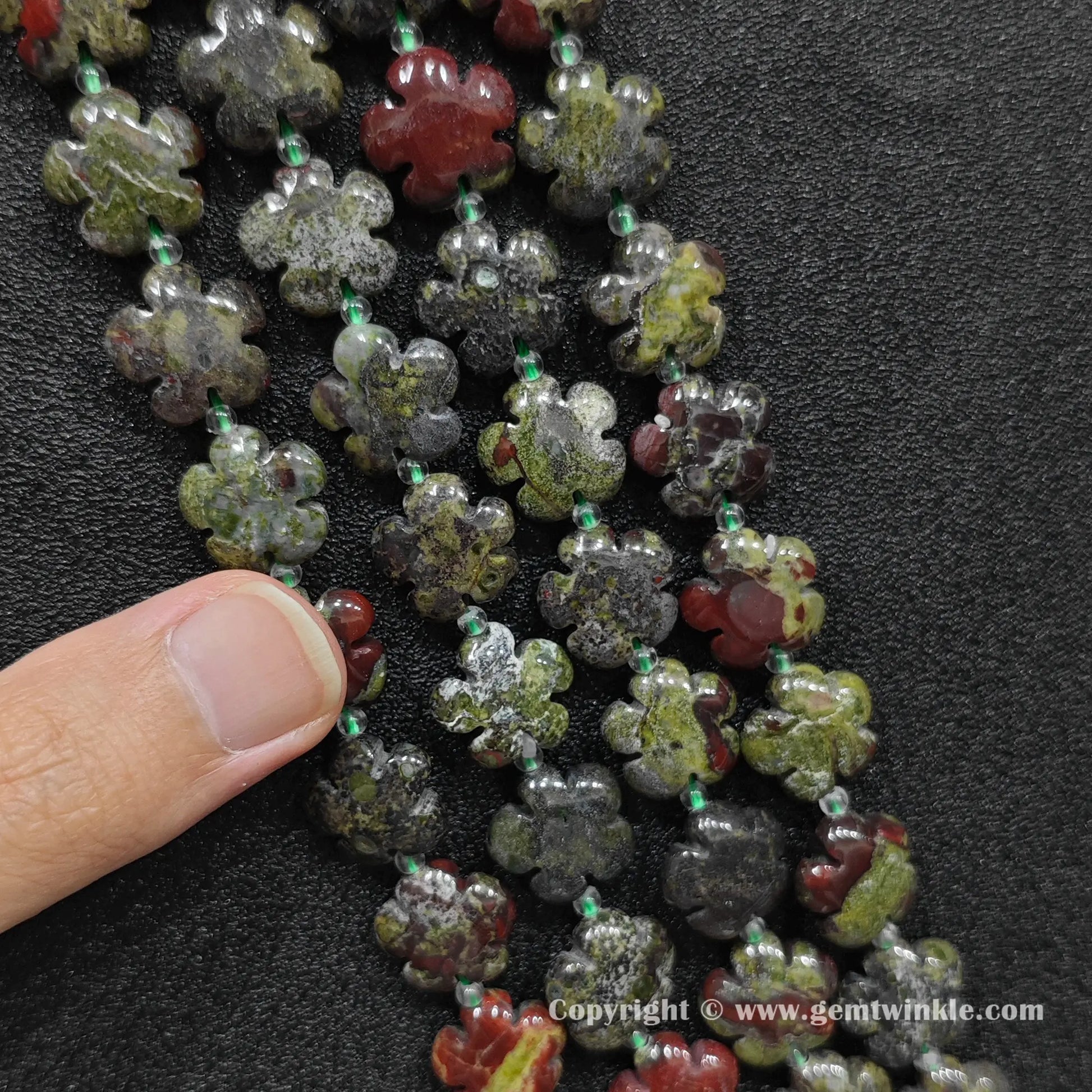 Natural dragon blood jasper plum blossom carved bead strand held over hand showing size scale