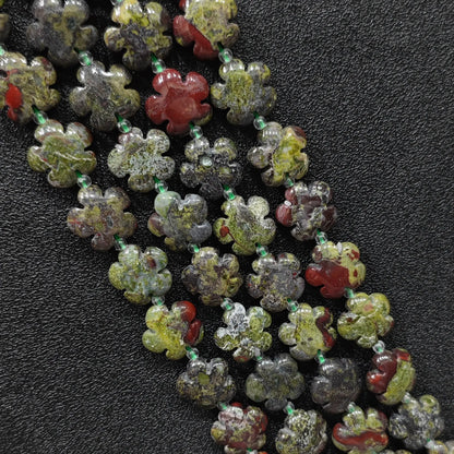 Macro closeup of dragon blood jasper plum blossom carved beads 15mm showing green and red mottled texture