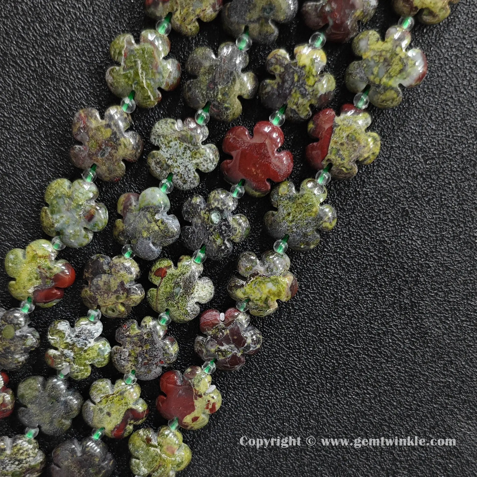 Angled view of natural dragon blood stone floral carved gemstone strands laid together