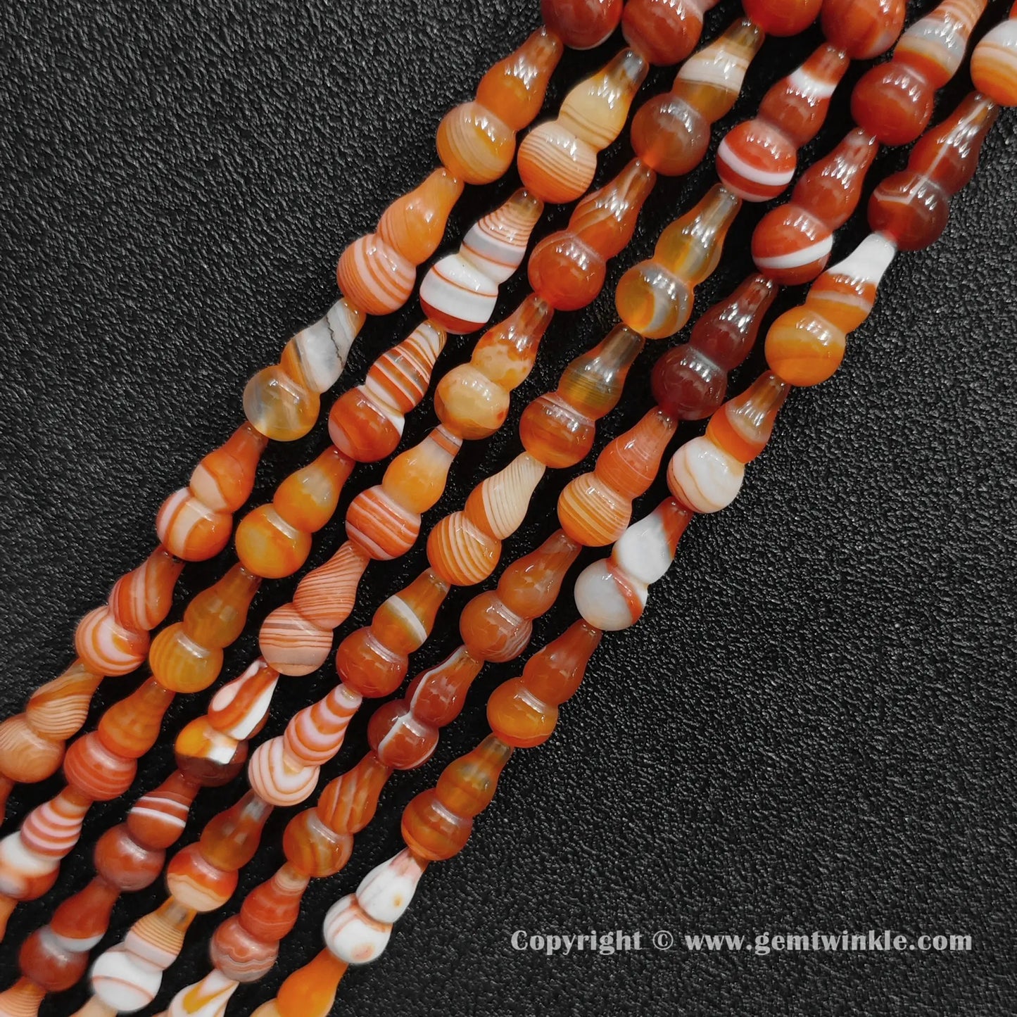 Angled view of smooth polished color-dyed banded agate calabash cut gemstone strands