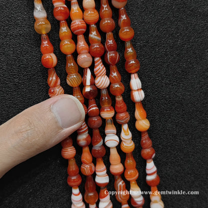 Color-dyed banded agate gourd shaped bead strand held over hand for size scale